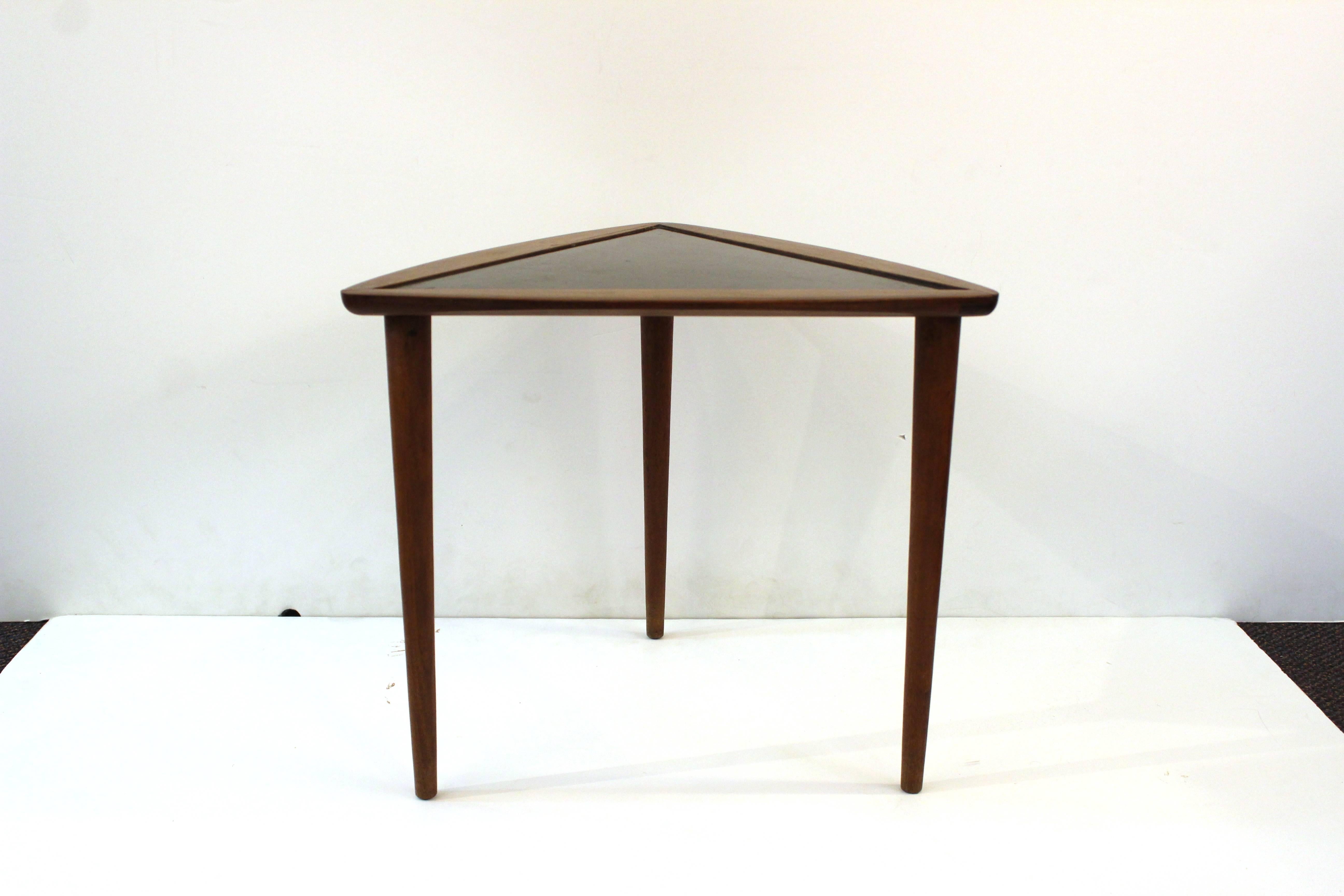 A small side table, triangular shaped and stained a deep brown. Black painted accent on tabletop. 

110515.

 