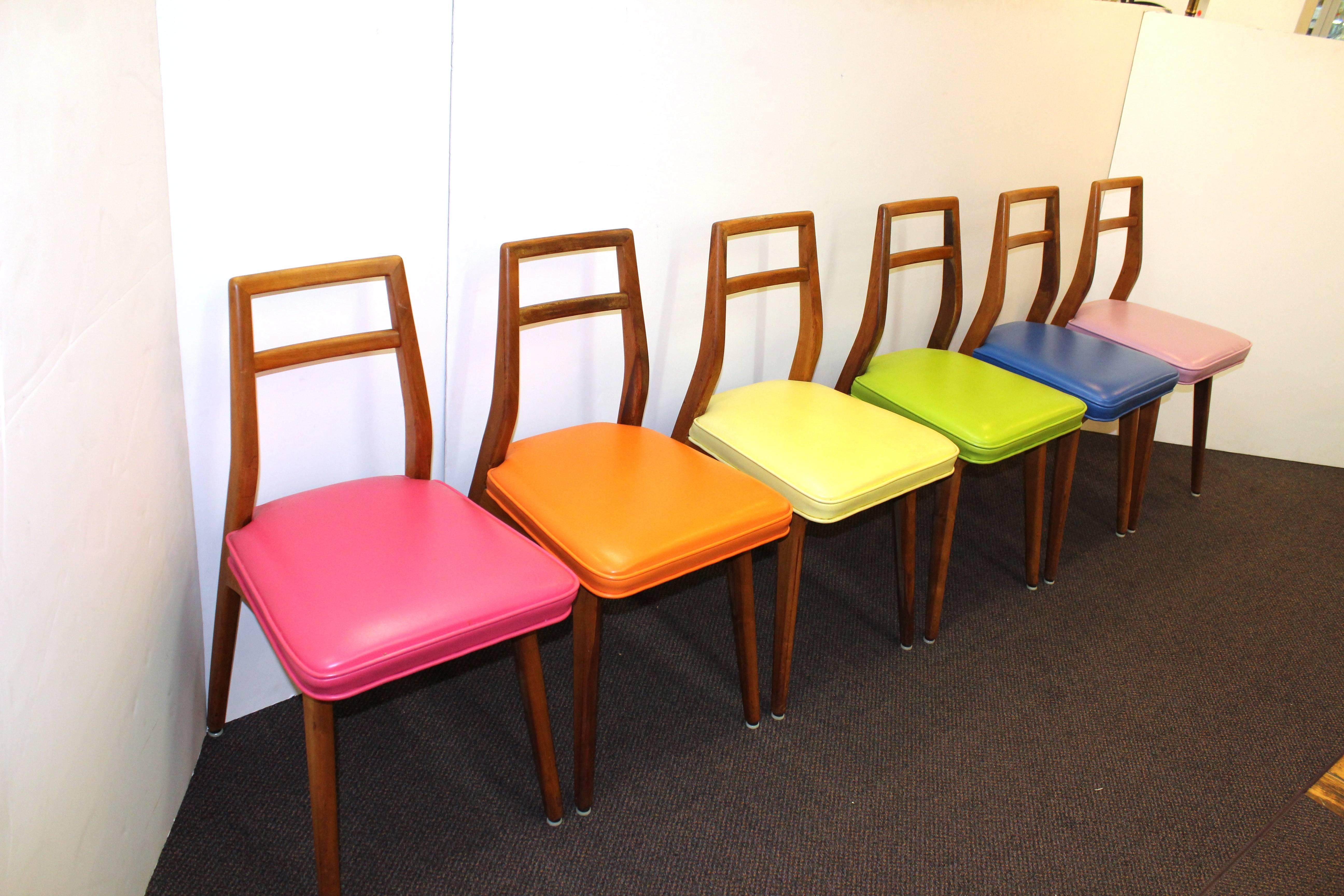 A set of six dining chairs each later re-upholstered in pink, orange, yellow, green, blue and lilac upholstery. 

110518.