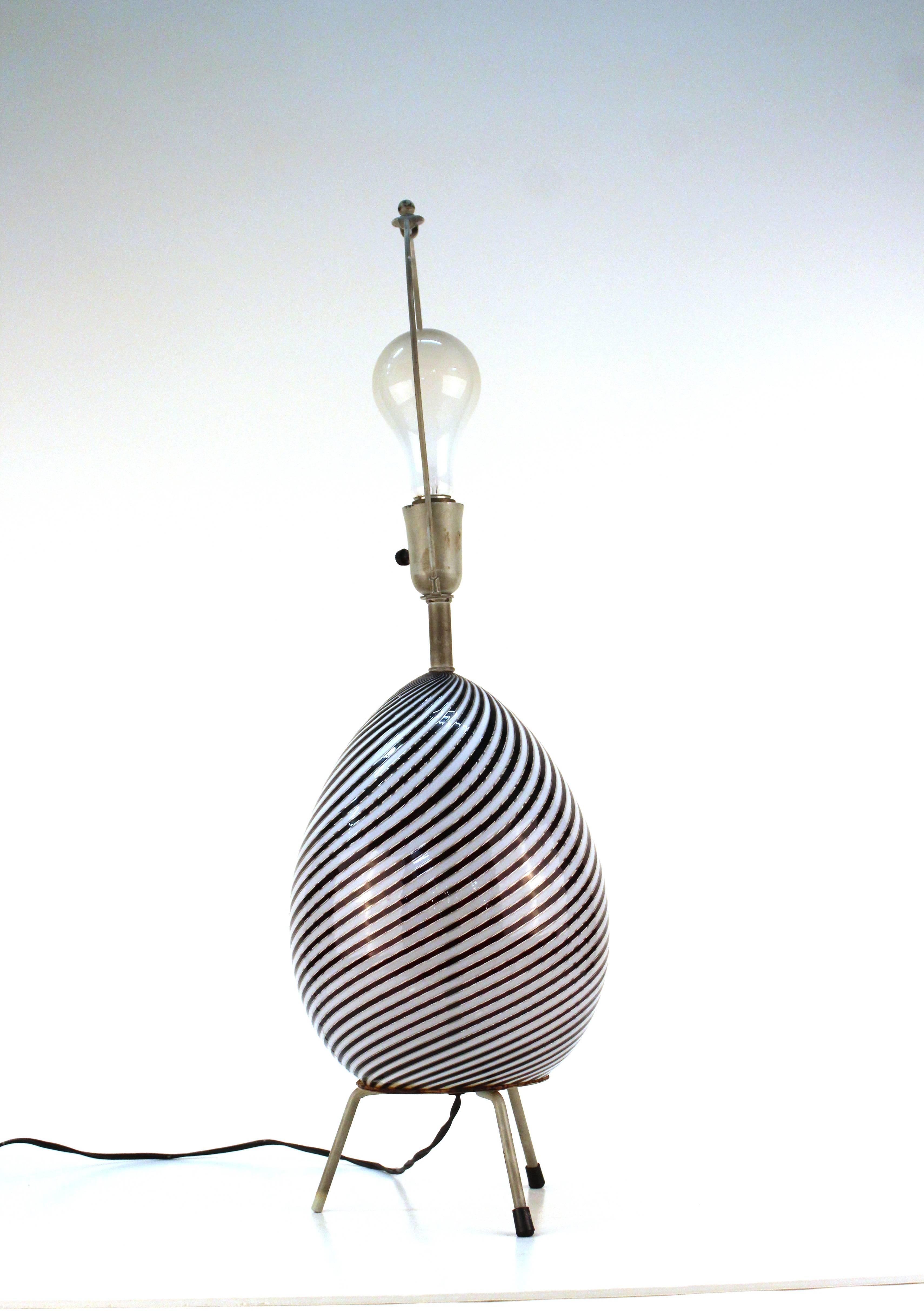 A Venini Murano Glass egg lamp with white and deep plum swirls, Mounted on tripod legs. 

110525.