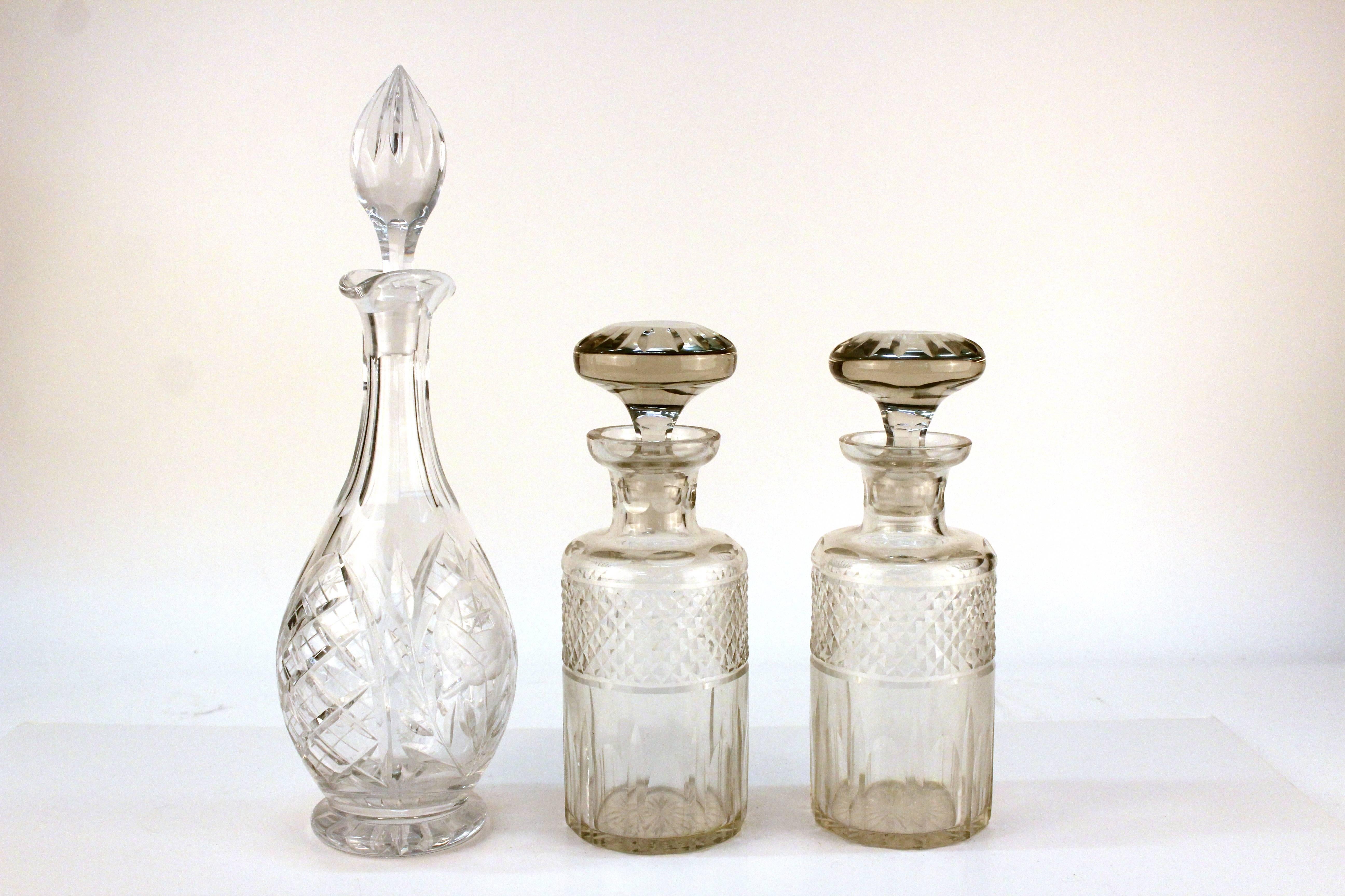 Set of three decanters. Includes a pair in a darker clear crystal, and a large bonus decanter with etched details and a flame stopper. 

Measures: Pair: 10 in. H x 3.5 in. D
Large: 16 in H x 4 in. D.

110596.

