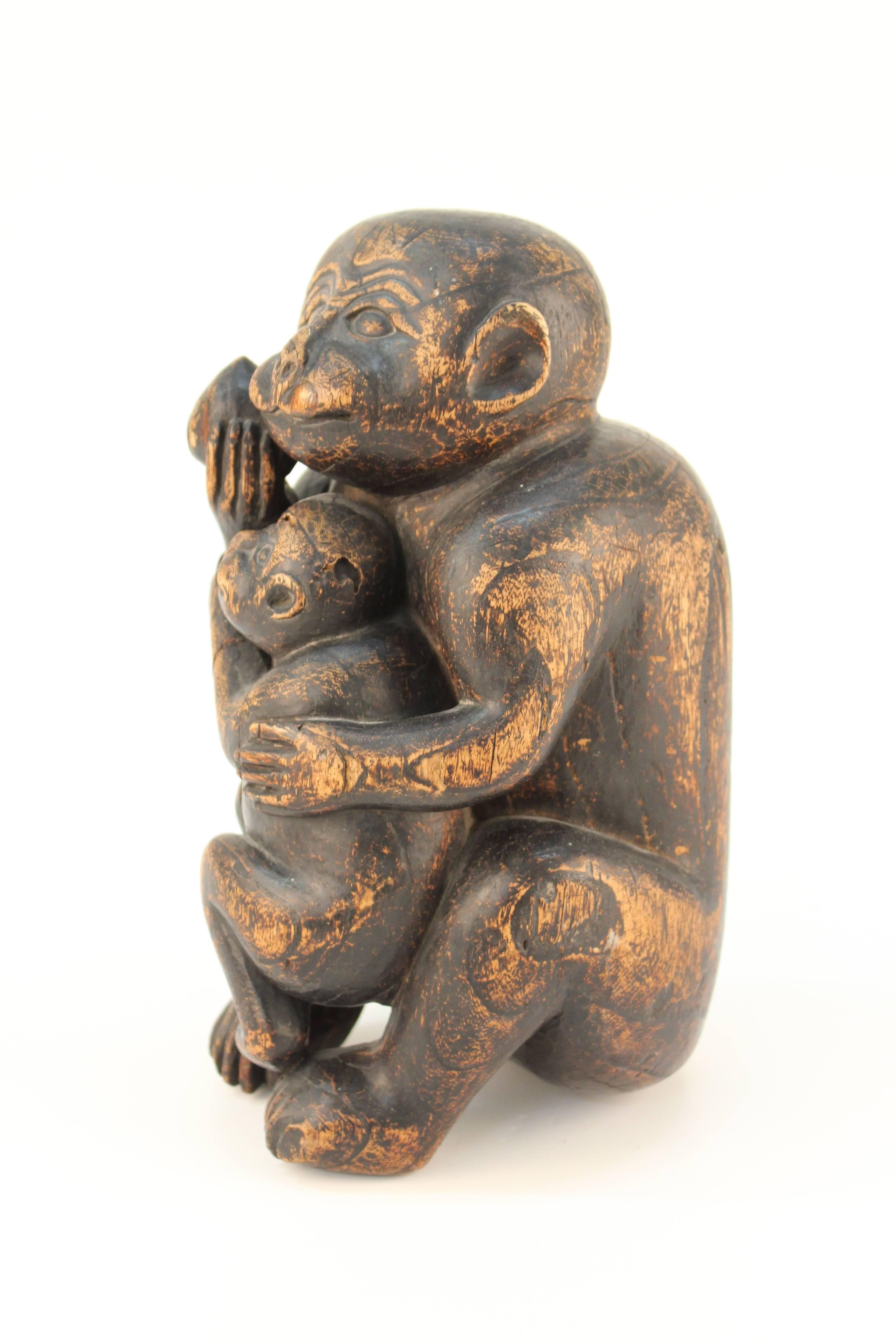 A sculpture of a monkey holding a peach in one hand and her baby in another. Carved out of wood. Despite some signs of wear to the wood, the sculpture remains in good vintage condition. 32495

  