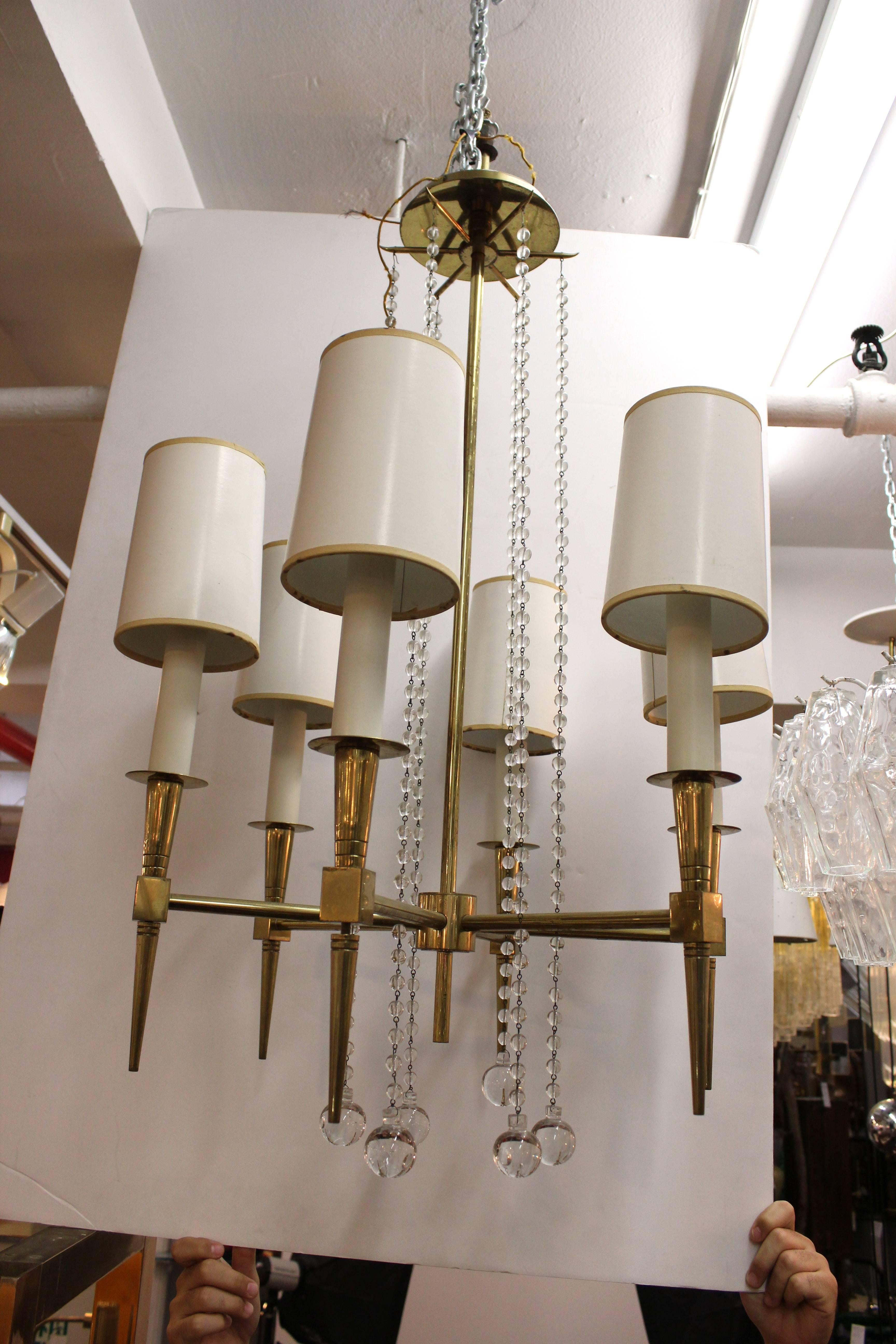 A pair of solid brass and glass beaded six-light chandeliers by Tommi Parzinger includes linen shades. 110636
  