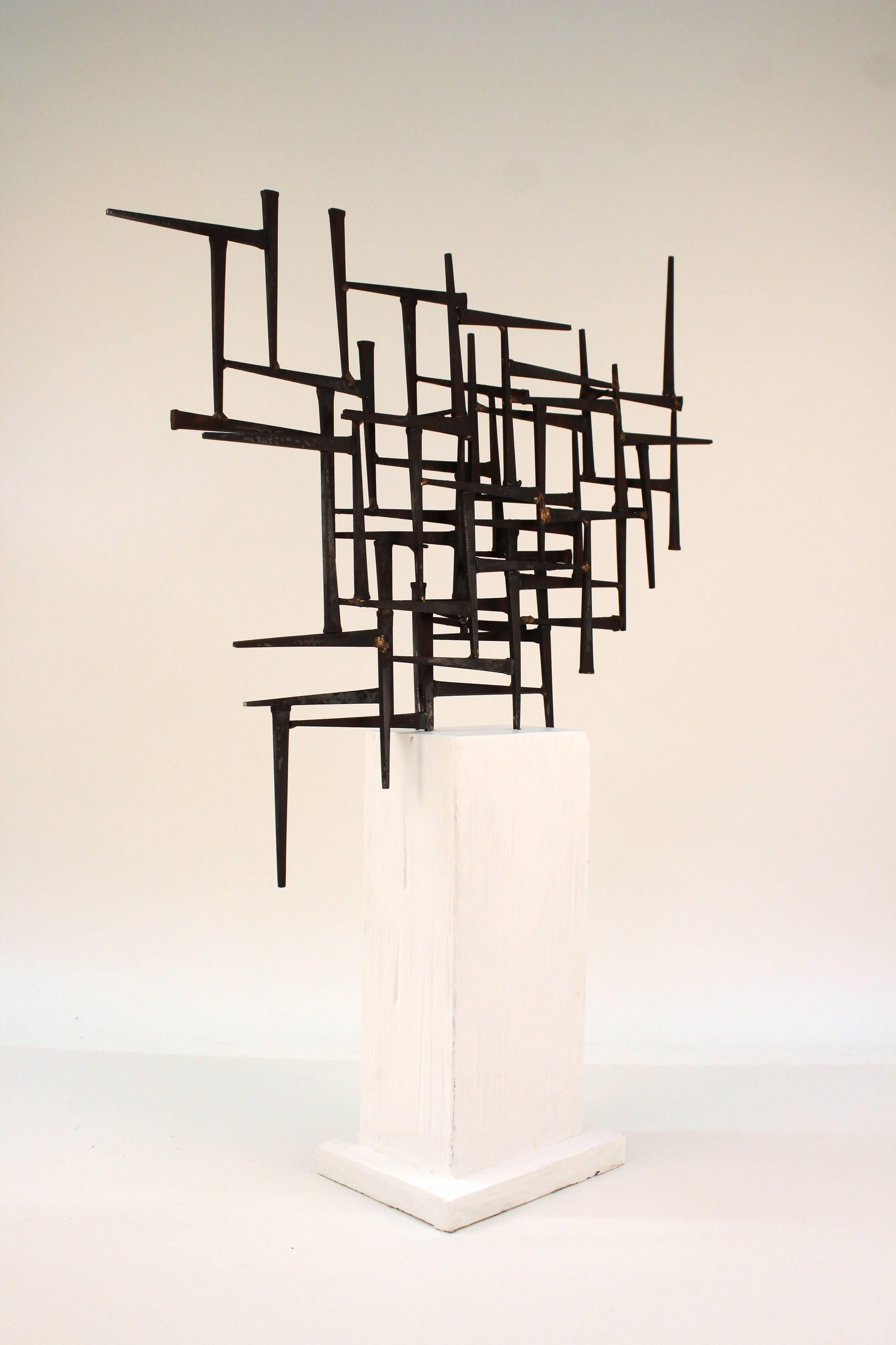 A sculpture by DeGroot made of many nails placed in a geometric abstract shape. Mounted on white painted wooden base. 

110623

  