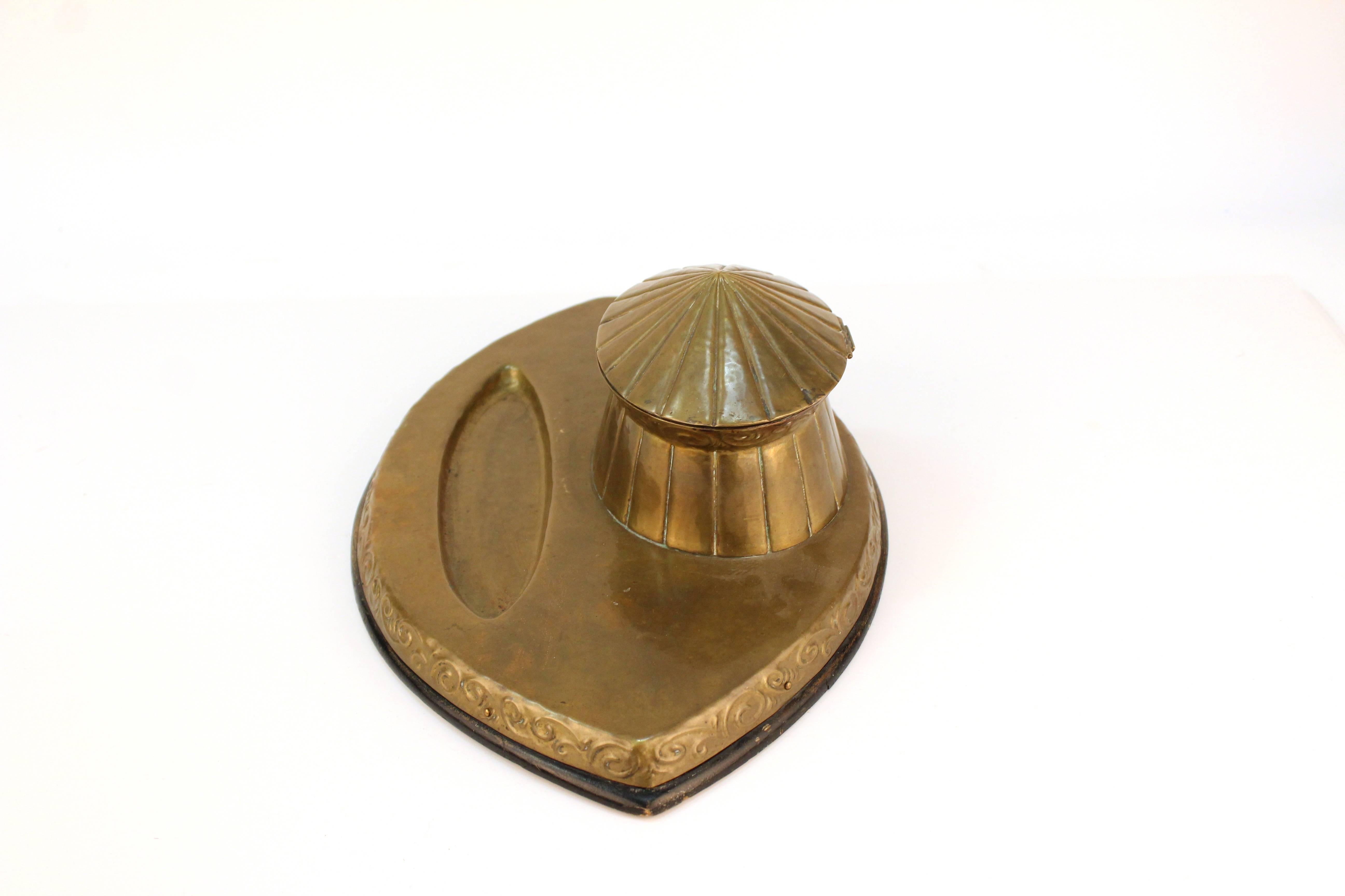 A vintage brass inkwell of the Arts & Crafts Movement. A circus tent shaped pot sits on an almond shaped base with a small indent for pens, intricate swirls decorate the sides. In good vintage condition.

110607

   

 