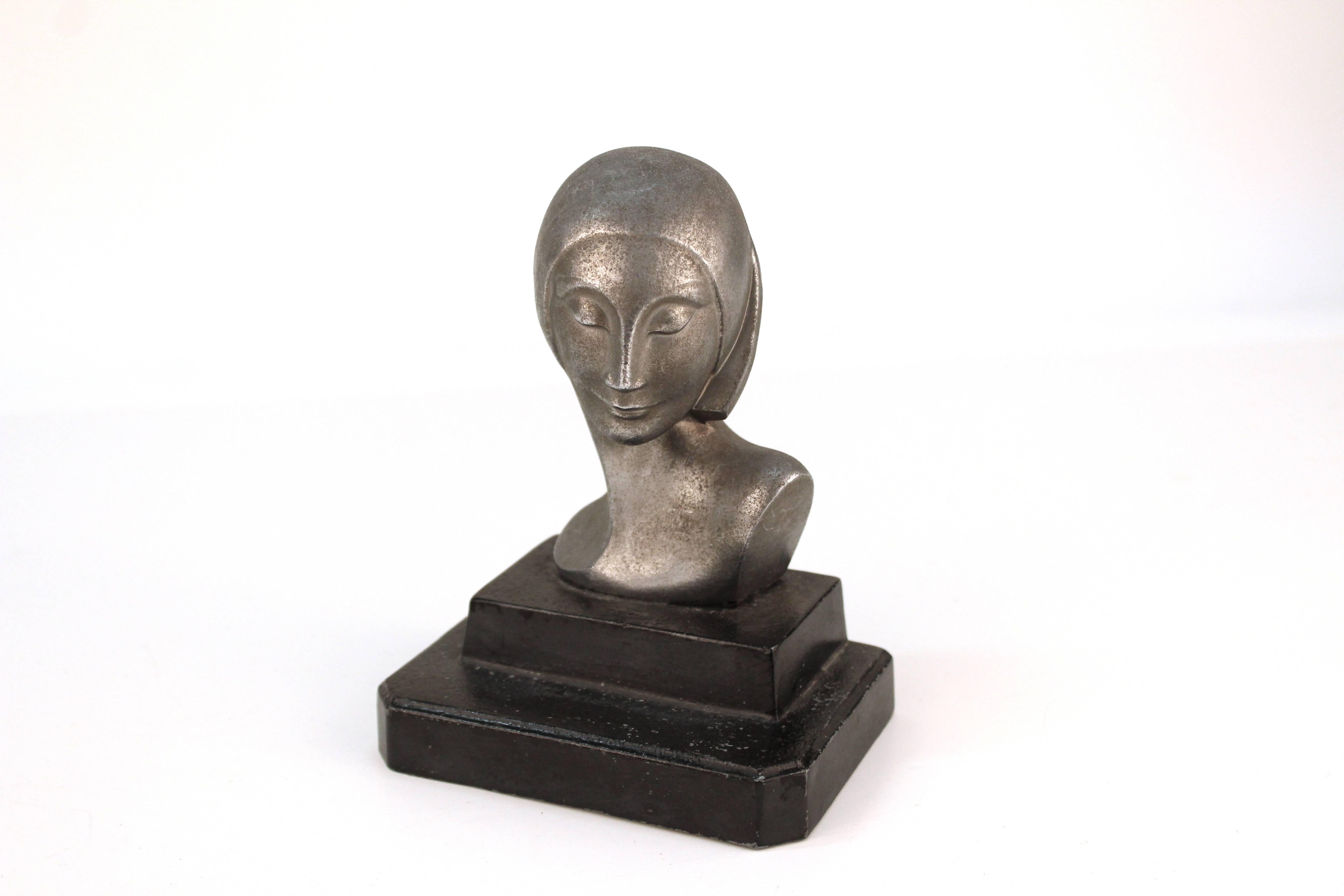 A stylized bust of a young women, crafted in aluminium and mounted on a black base. 

110608

    