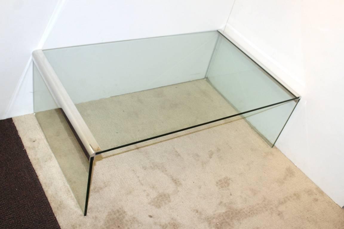 Modernist glass waterfall table features chrome edges and glass plate top and legs. Dating from the late twentieth century it is in good vintage condition and has wear consistent with age and use. 