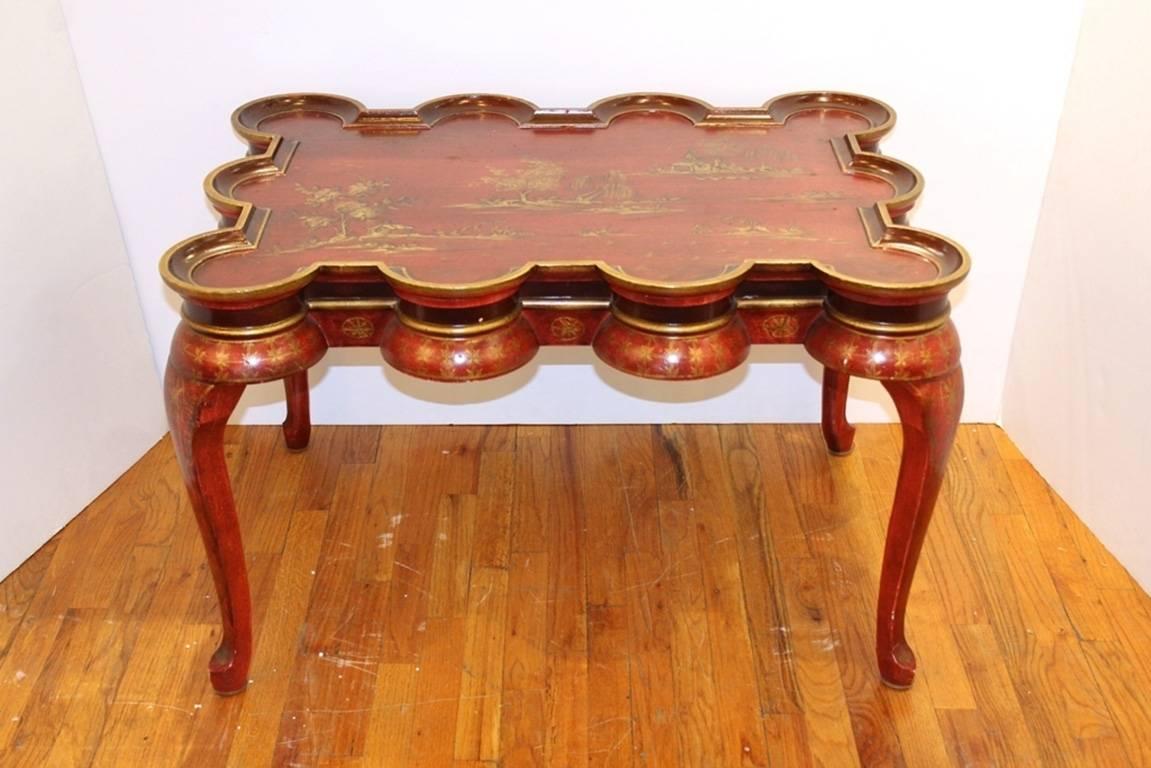 This chinoiserie coffee table in red and gold features curved legs and decorative scenes on the top.