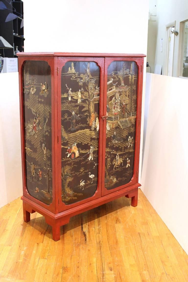 This chinoiserie cabinet in red and black features fantastical illustrated scenes of godly life on both the exterior and interior of the cabinet.