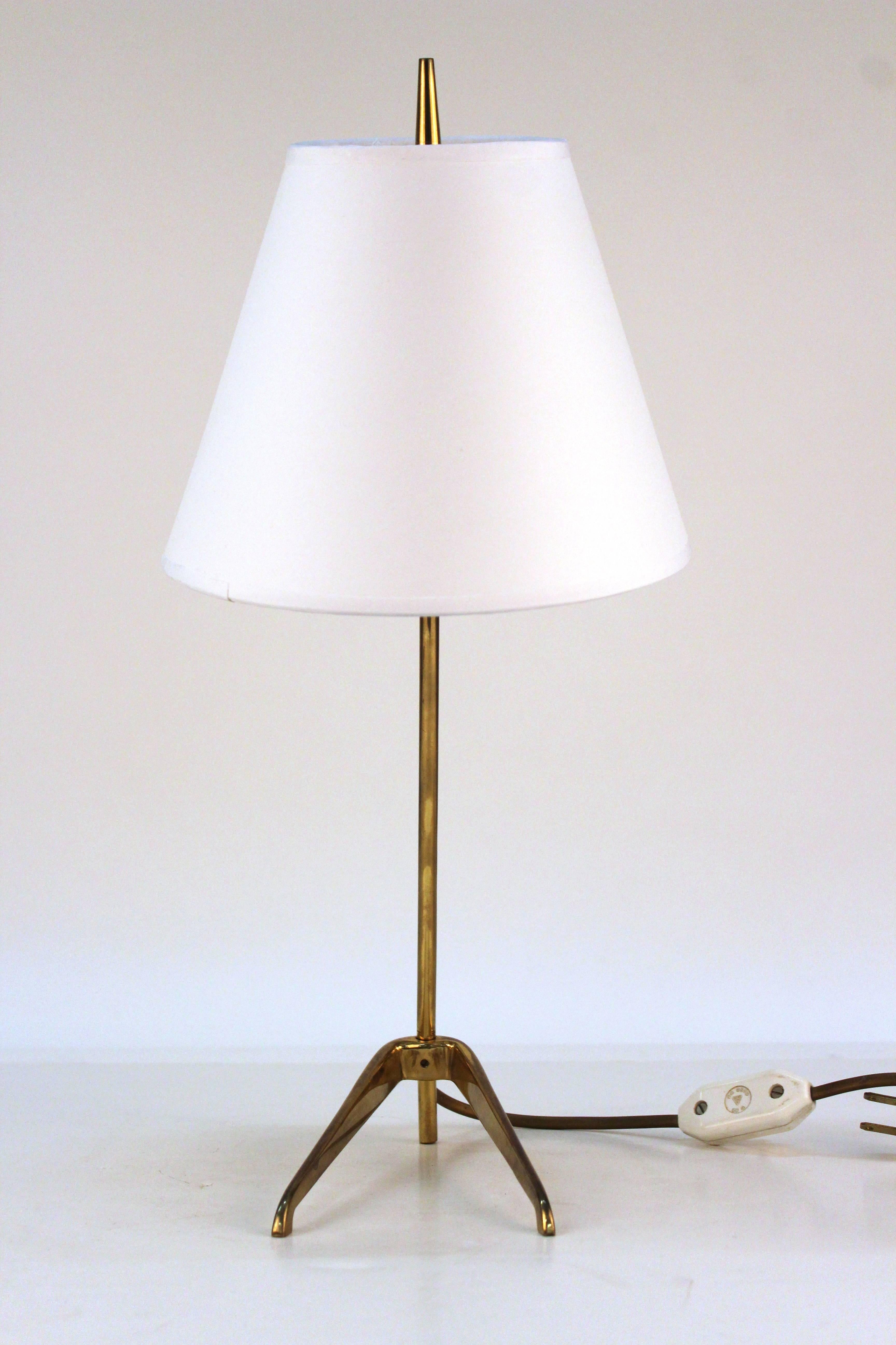 A Mid-Century desk lamp produced in Germany leans on two brass legs at a stylish angle.