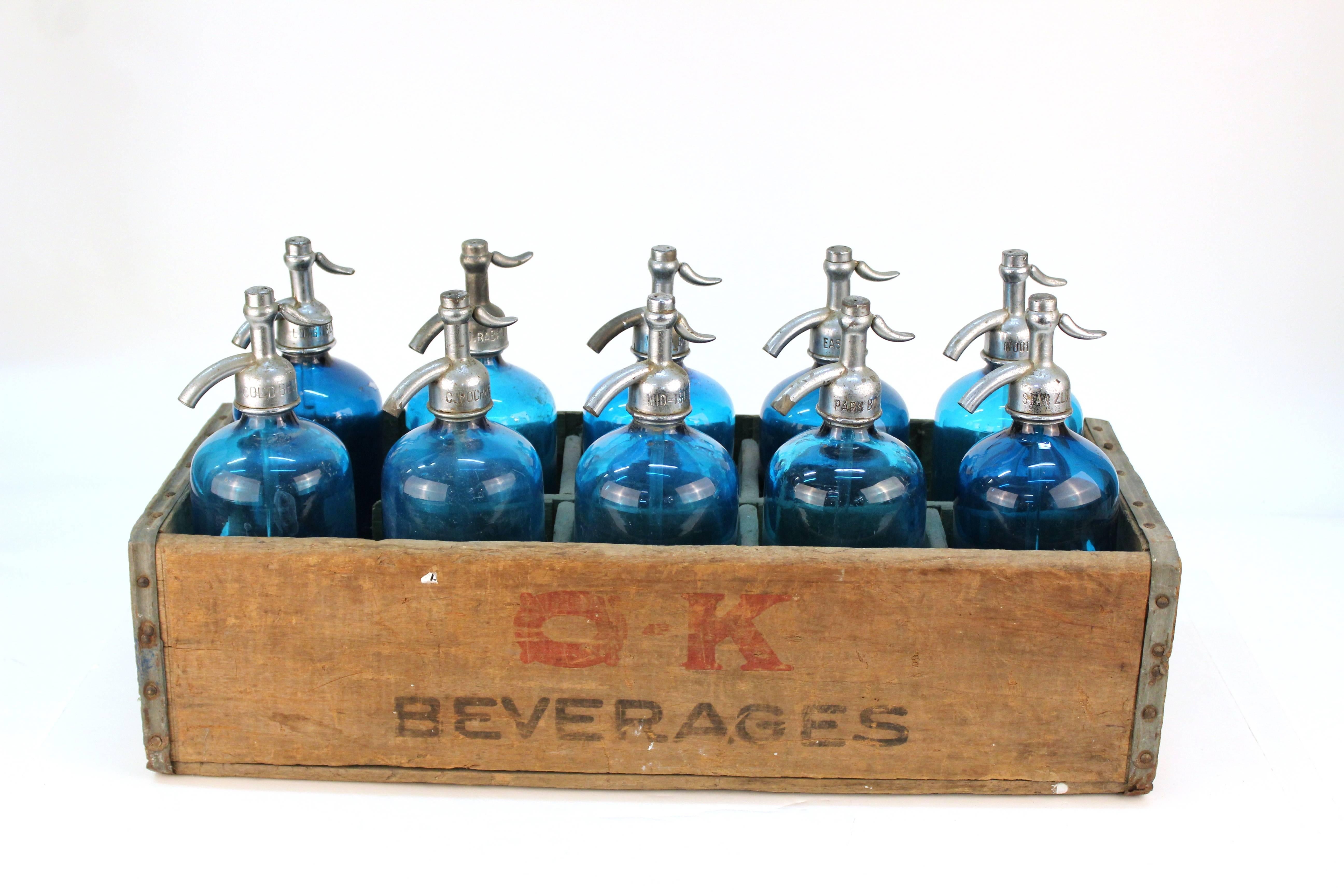 Vintage peacock blue seltzer bottles with silver-tone tops. Marked with New York Brooklyn, Bronx and Long Island. For individual sale. In very good condition. Crate for display only.