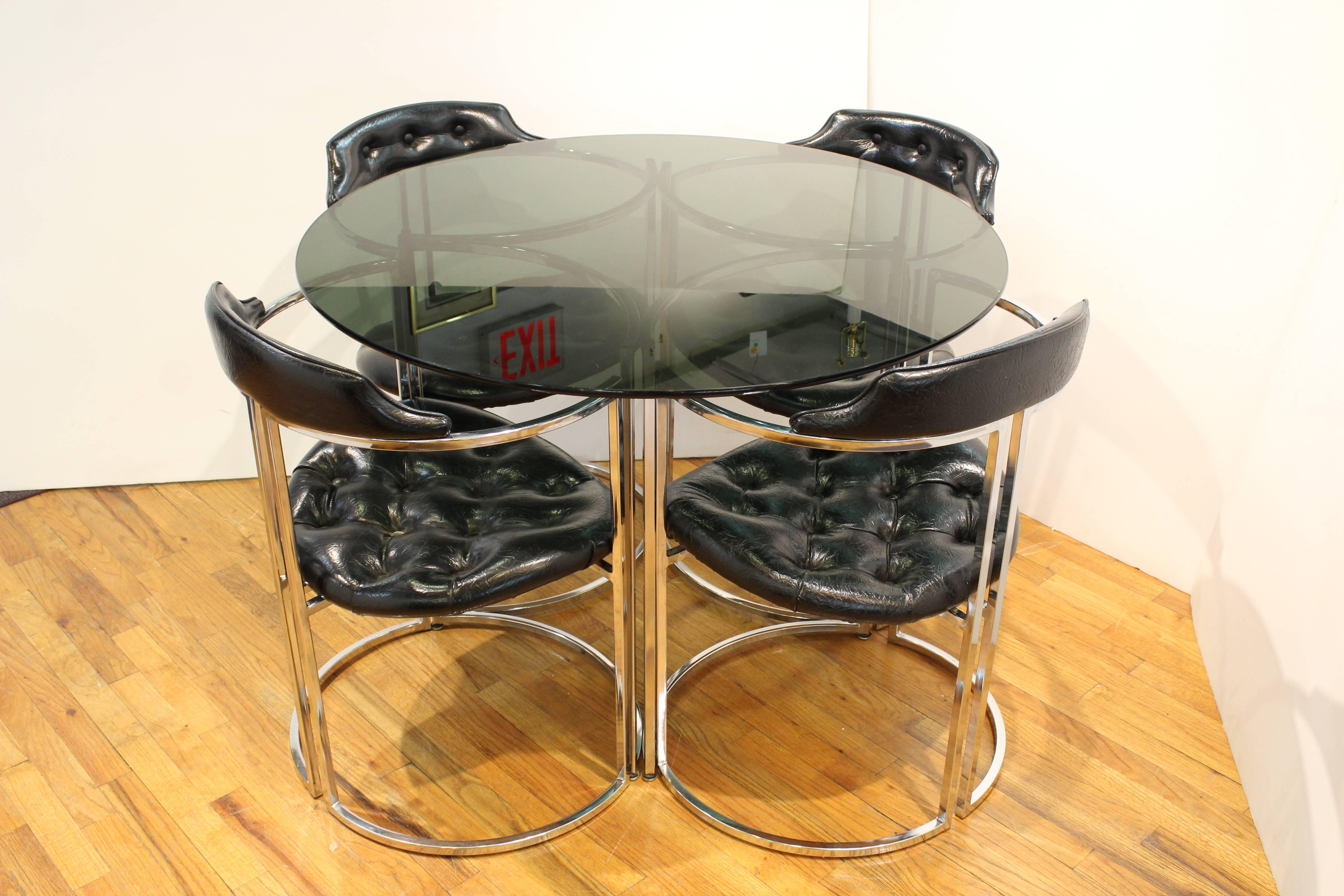 A dinette set in chrome, smoked glass and vinyl done in the style of Milo Baughman. Includes original label and punch card. Wear to the upholstery includes visible restoration. Some glass grips missing on the tabletop.

Measure: Table 42