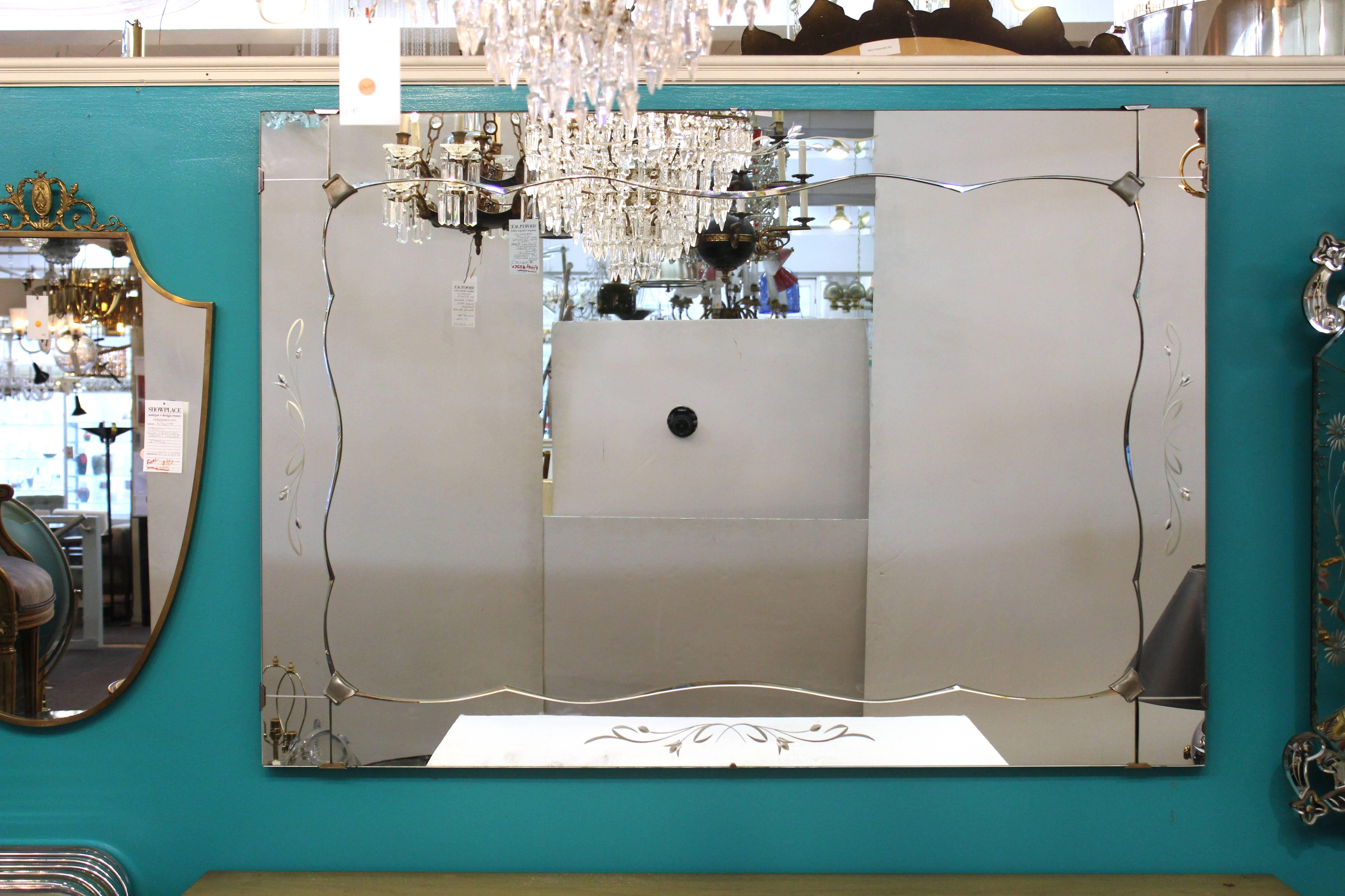 A Hollywood Regency large mirror with etched borders and chrome scroll decorations in each corner.