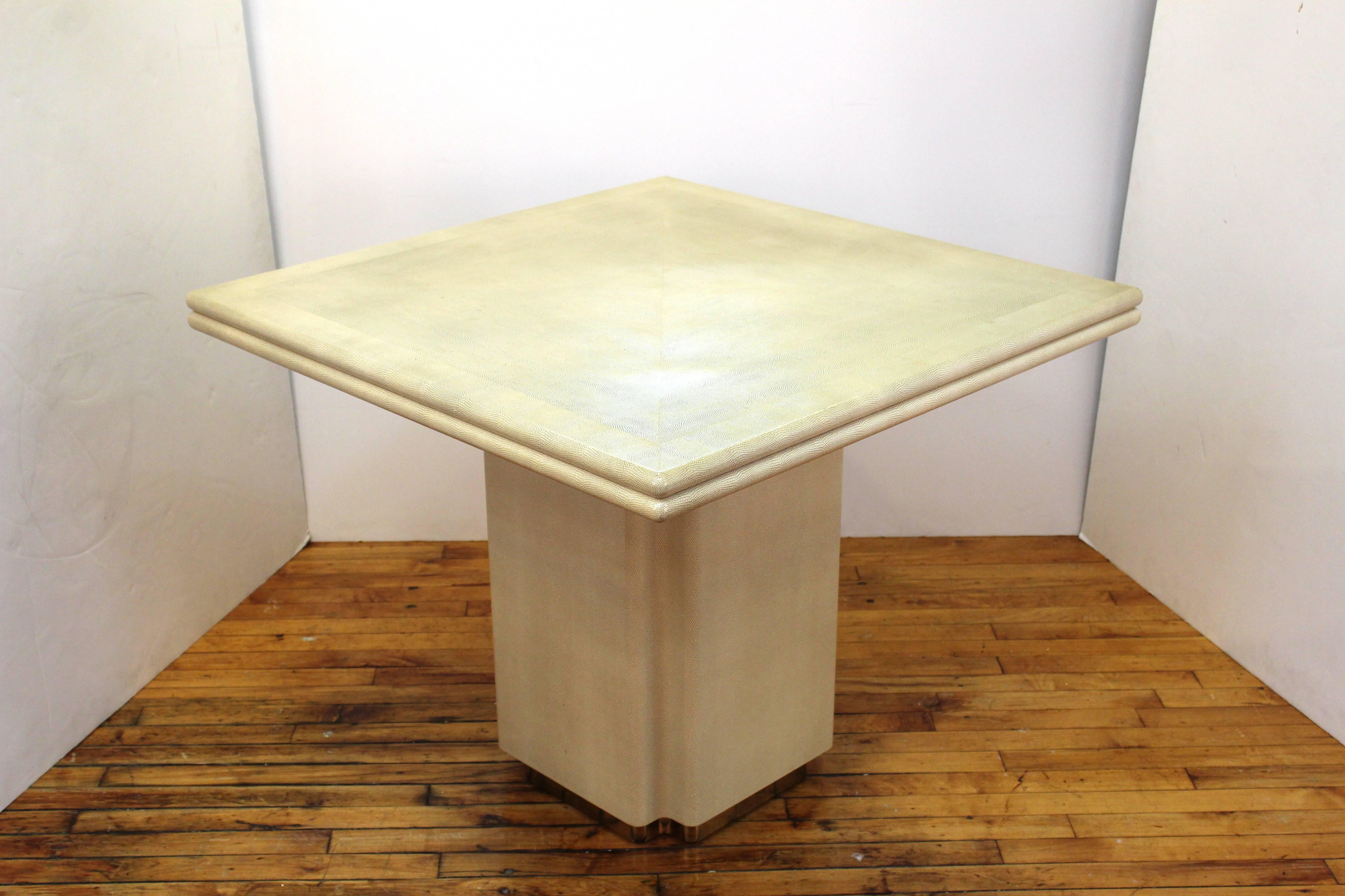 A square shagreen coffee table supported by a pedestal base. Cream with polished brass recessed stripe near the foot. In good vintage condition, consistent with age and use.