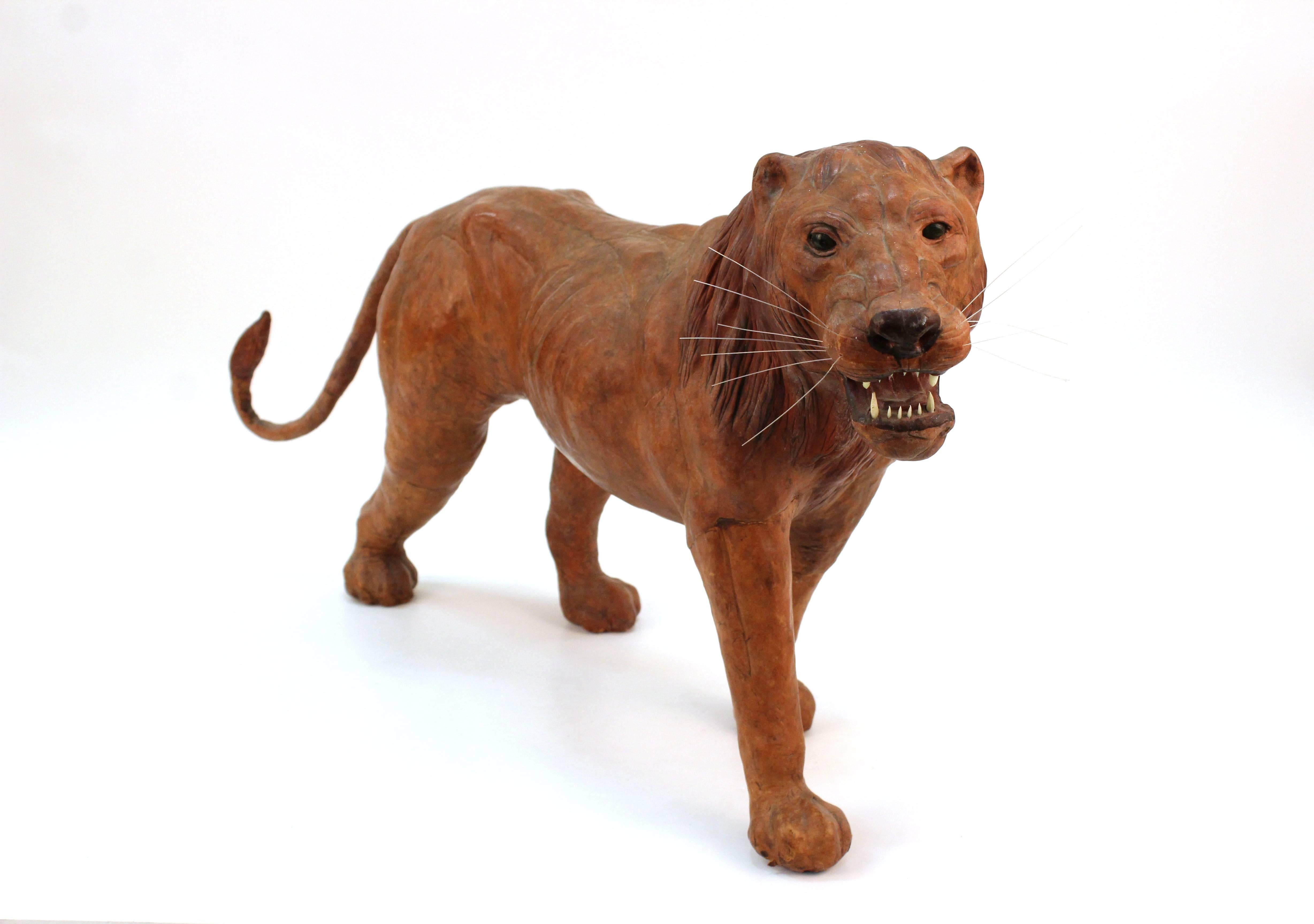 A sculpture of a prowling lion in rust colored leather. Includes lifelike whiskers and pronounced teeth. In good vintage condition.