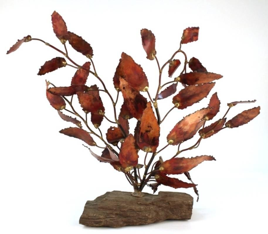 A Brutalist sculpture of a bush made of torch cut metal and mounted on a stone base. The artist has signed the sculpture 'DALE' to one of the leaves. This piece is in good condition, consistent with age and use.