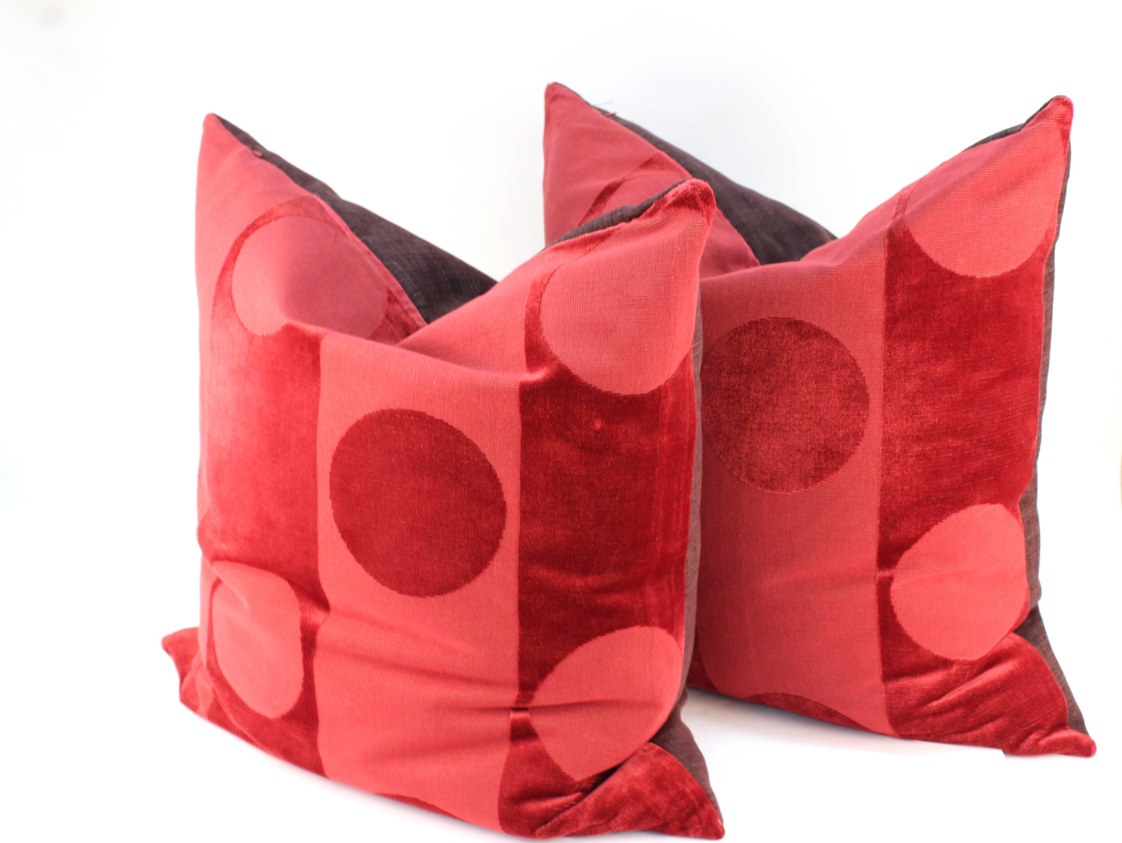 A pair of contemporary down pillows in Clarence House Fabric. The fabric is patterned in alternating shades of red with stripes and large dots. The pillows are in excellent condition.
