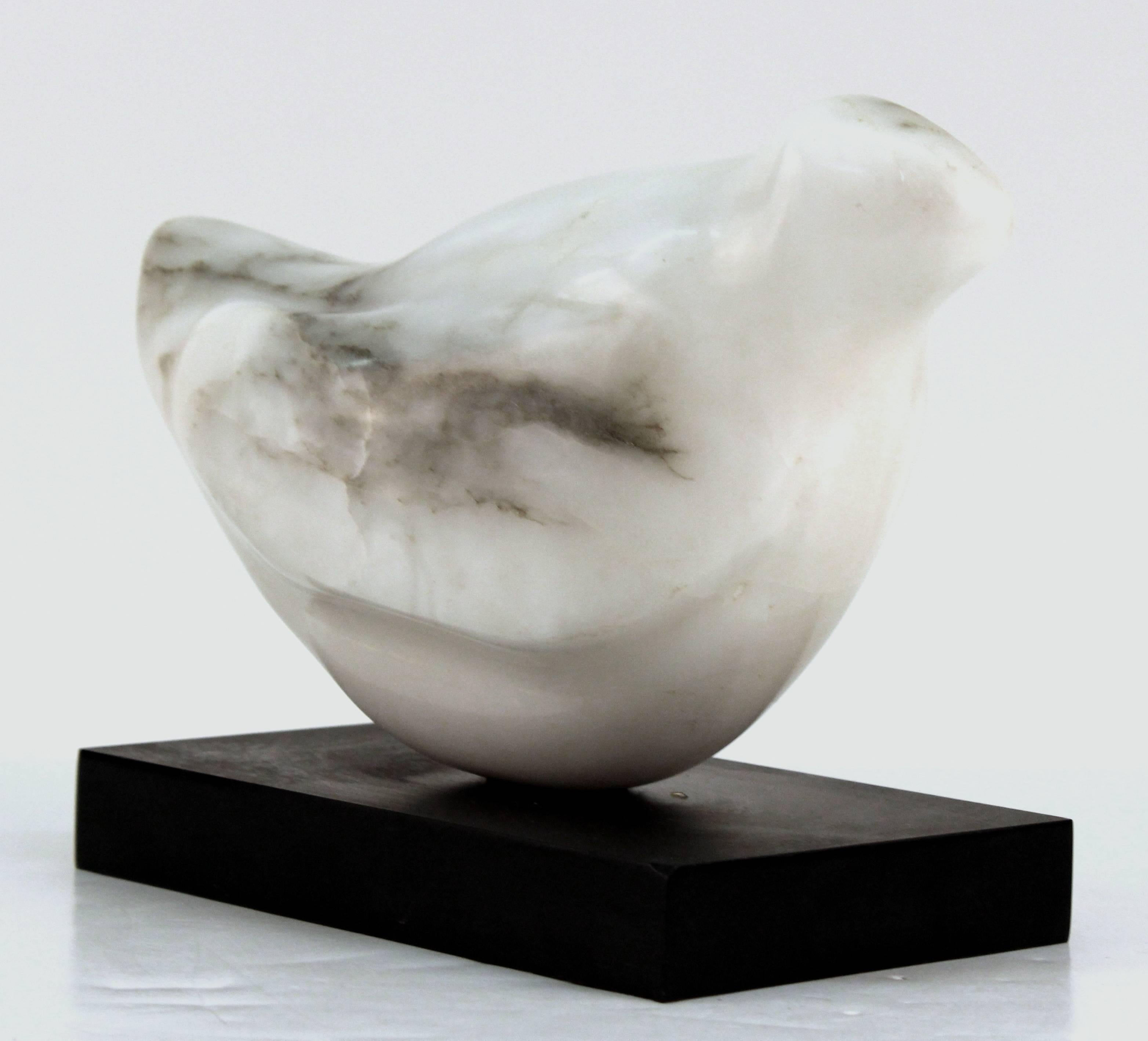 Modernist bird sculpture carved out of smooth white marble with black veins. The bird is in a seated position and rests on a black base. There is some scratching to the bottom of the base and the sculpture is in good vintage condition consistent