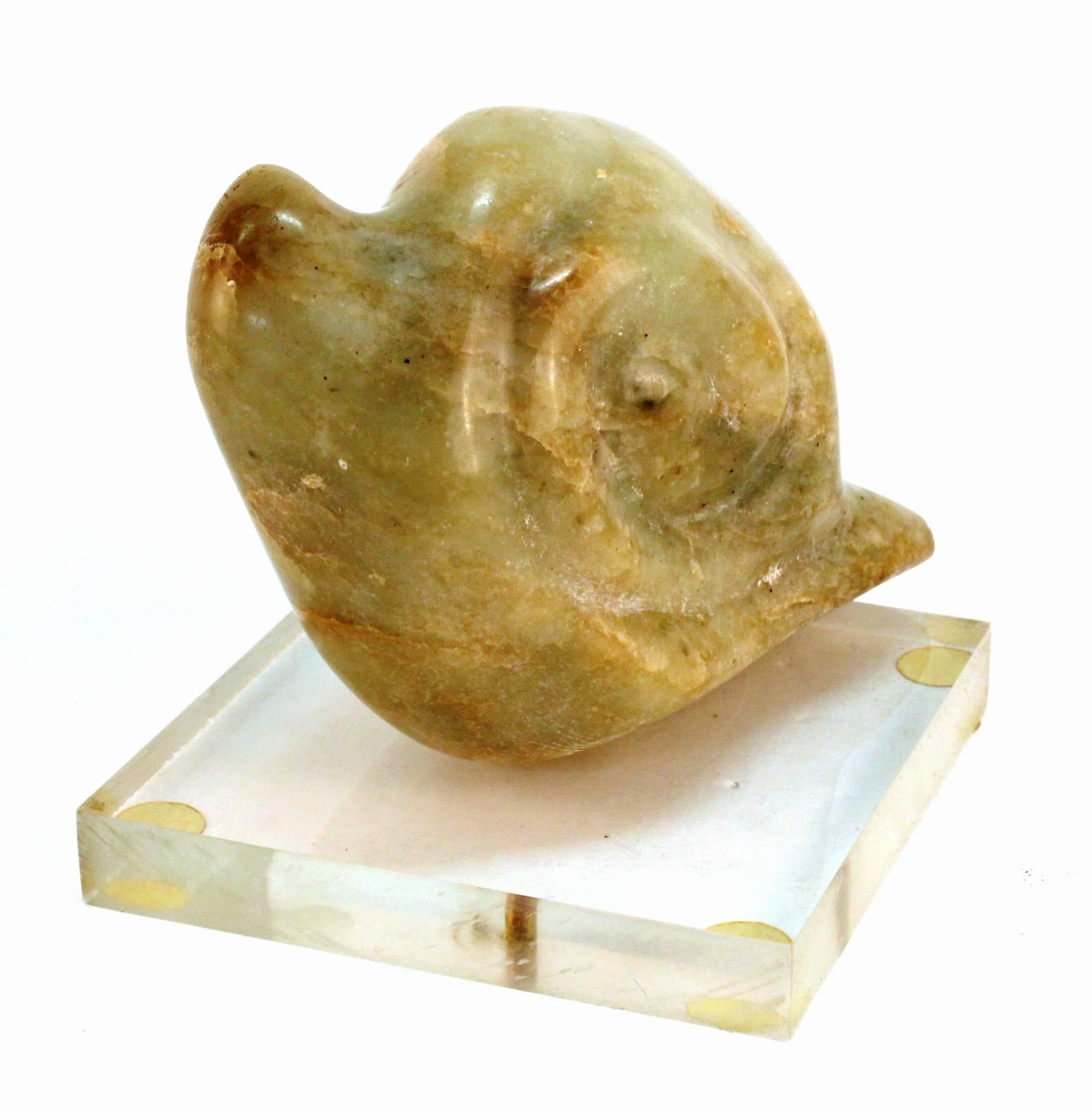 Stylized snail sculpture in a smooth green brown marble rests atop a clear Lucite base. The snail's head protrudes from its spiral form shell. Although there is some yellowing to the feet on the base and a few scratches to the underside, this