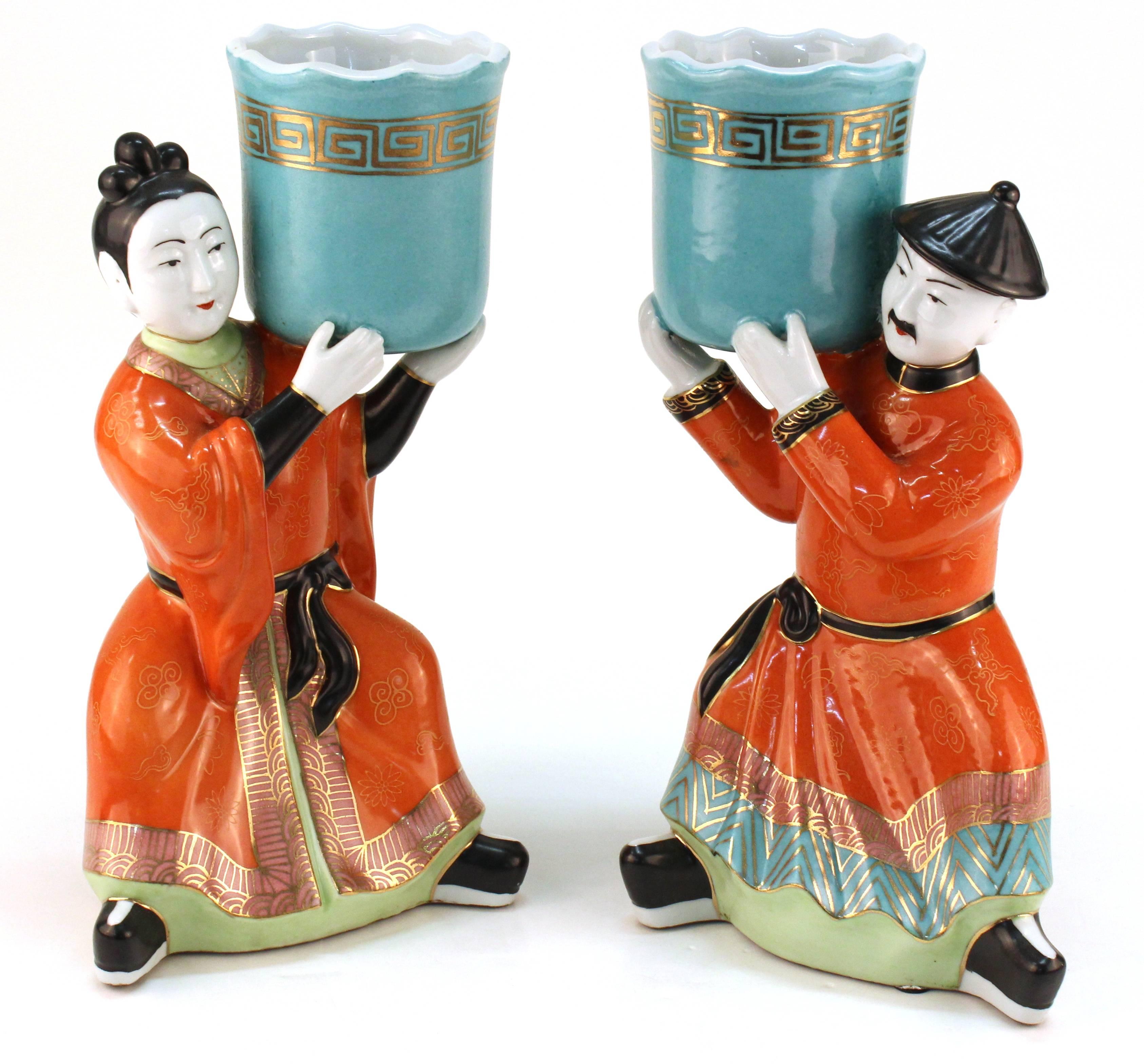 Gumps ceramic figures in the chinoiserie style each are shown holding an empty vessel that could function as a small planter or votive holder. The pair depicts a male and a female figure. In good vintage condition consistent with age and