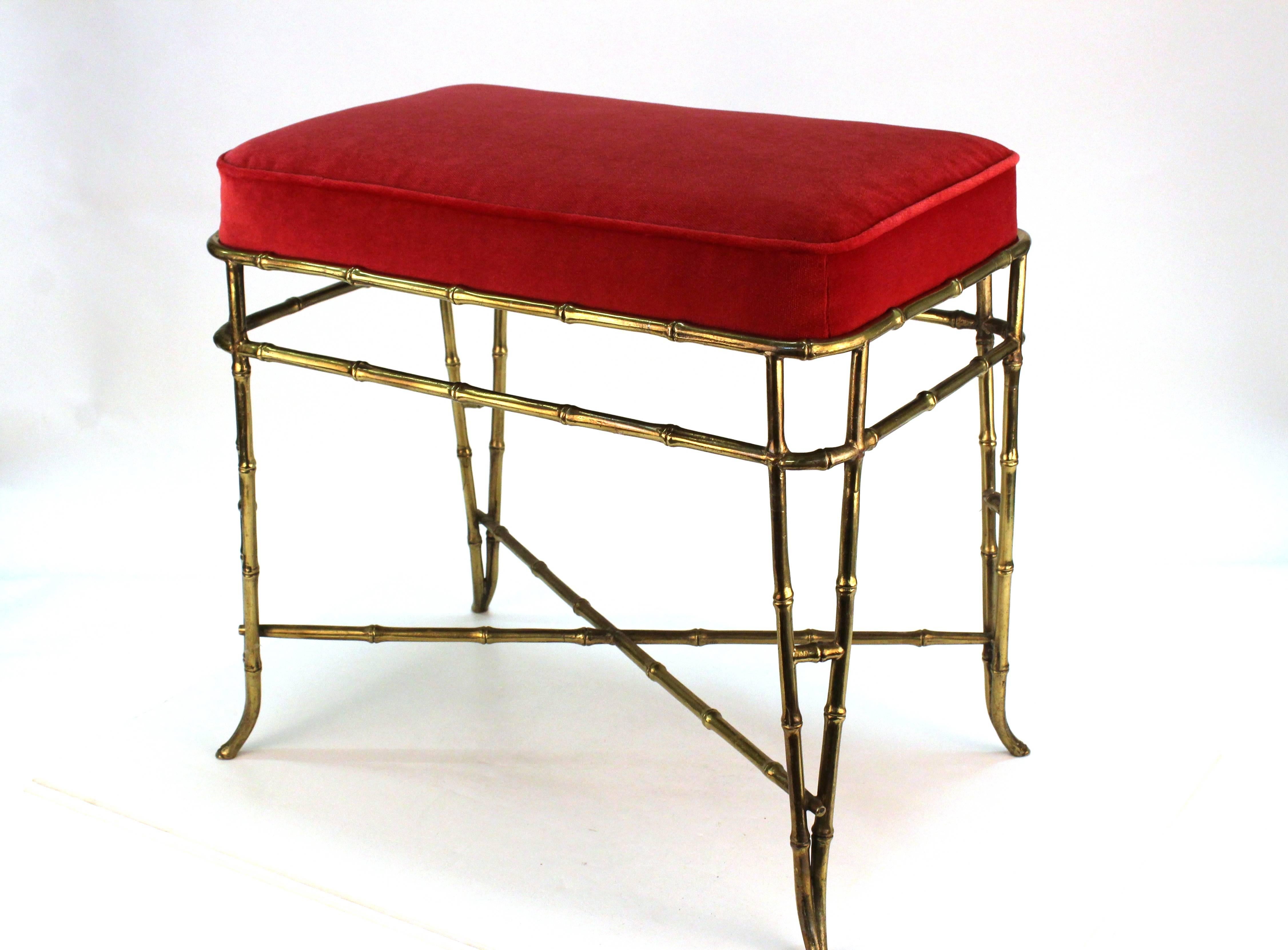 A faux bamboo bench in polished brass. Produced during the 1960s in the Hollywood Regency style. Newly re-upholstered in fuchsia velvet. In excellent condition.