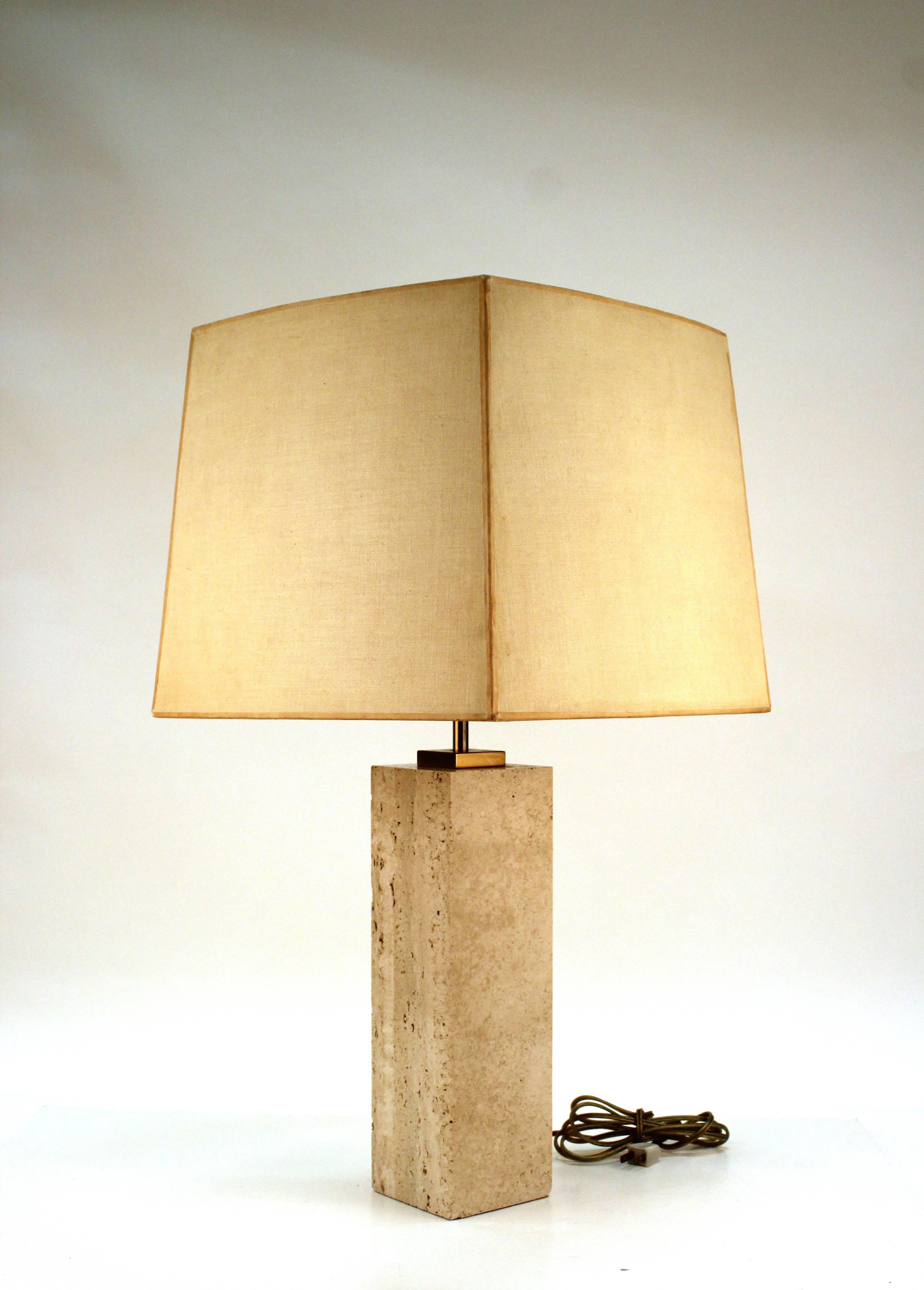 Travertine table lamp with brass detailing by Robsjohn-Gibbings. Includes the original shade which is in need of refurbishing. Despite two fleabite nicks on the base the lamp remains in very good condition.