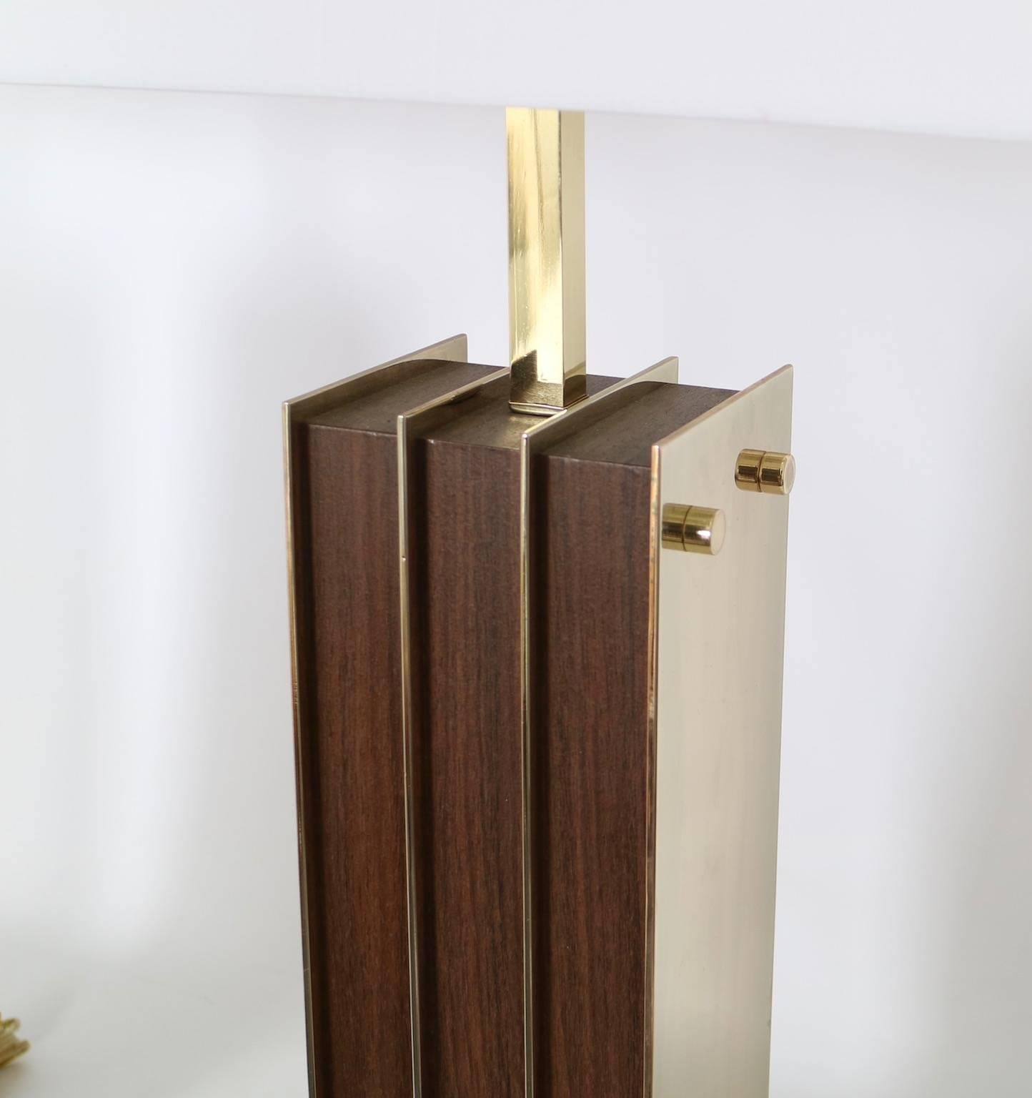 Mid-Century Modern wooden table lamps, with brass side plaques as accents, produced circa 1950s. This pair of lamps remains in excellent vintage condition with wear consistent with age. Each is fully restored with all new wiring and hardware. The