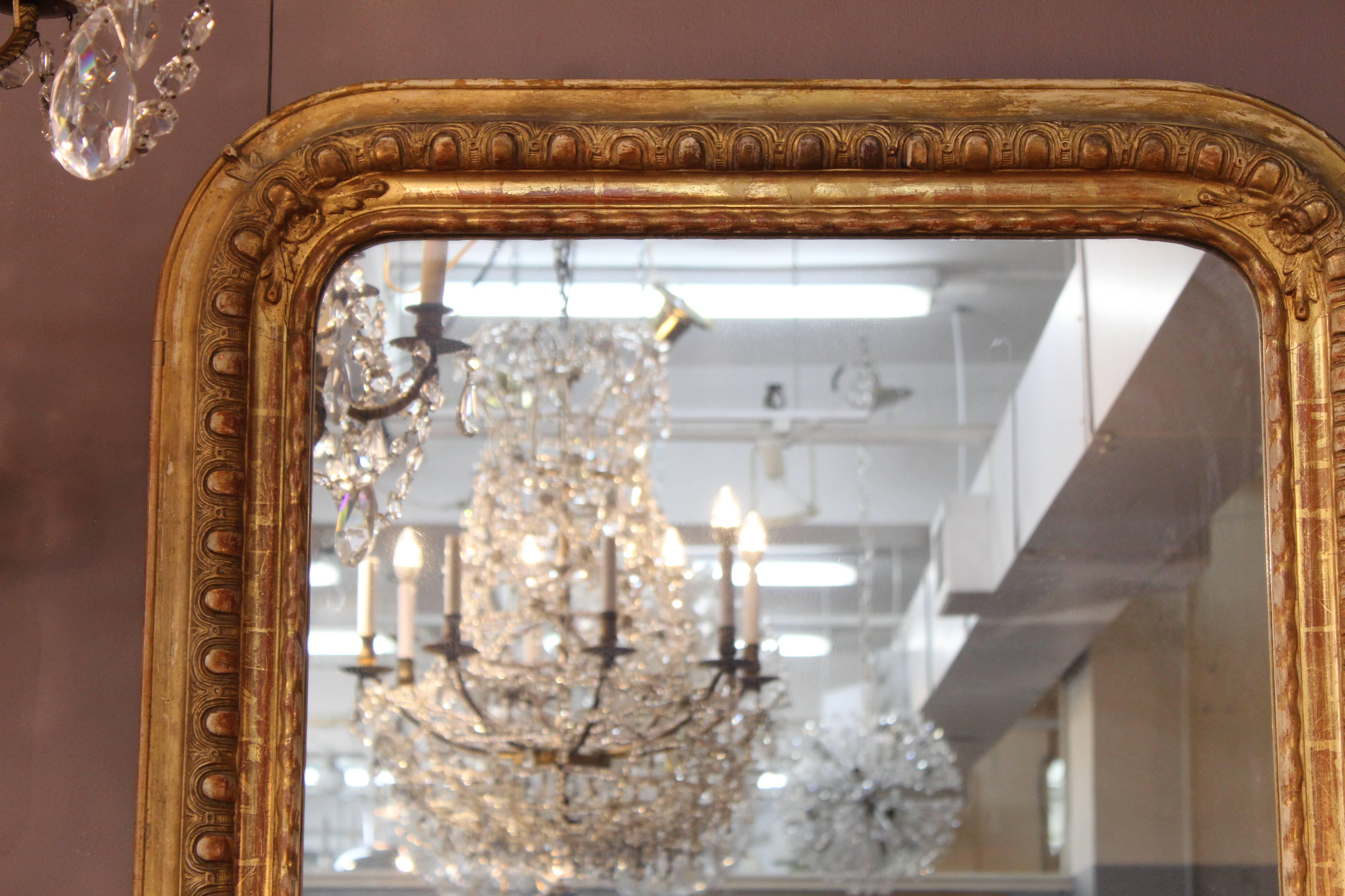 A French 19th century giltwood mirror produced during the reign of Louis-Philippe. The frame features refined egg-and-dart molding. Despite wear appropriate to age and use, the piece is in good condition.