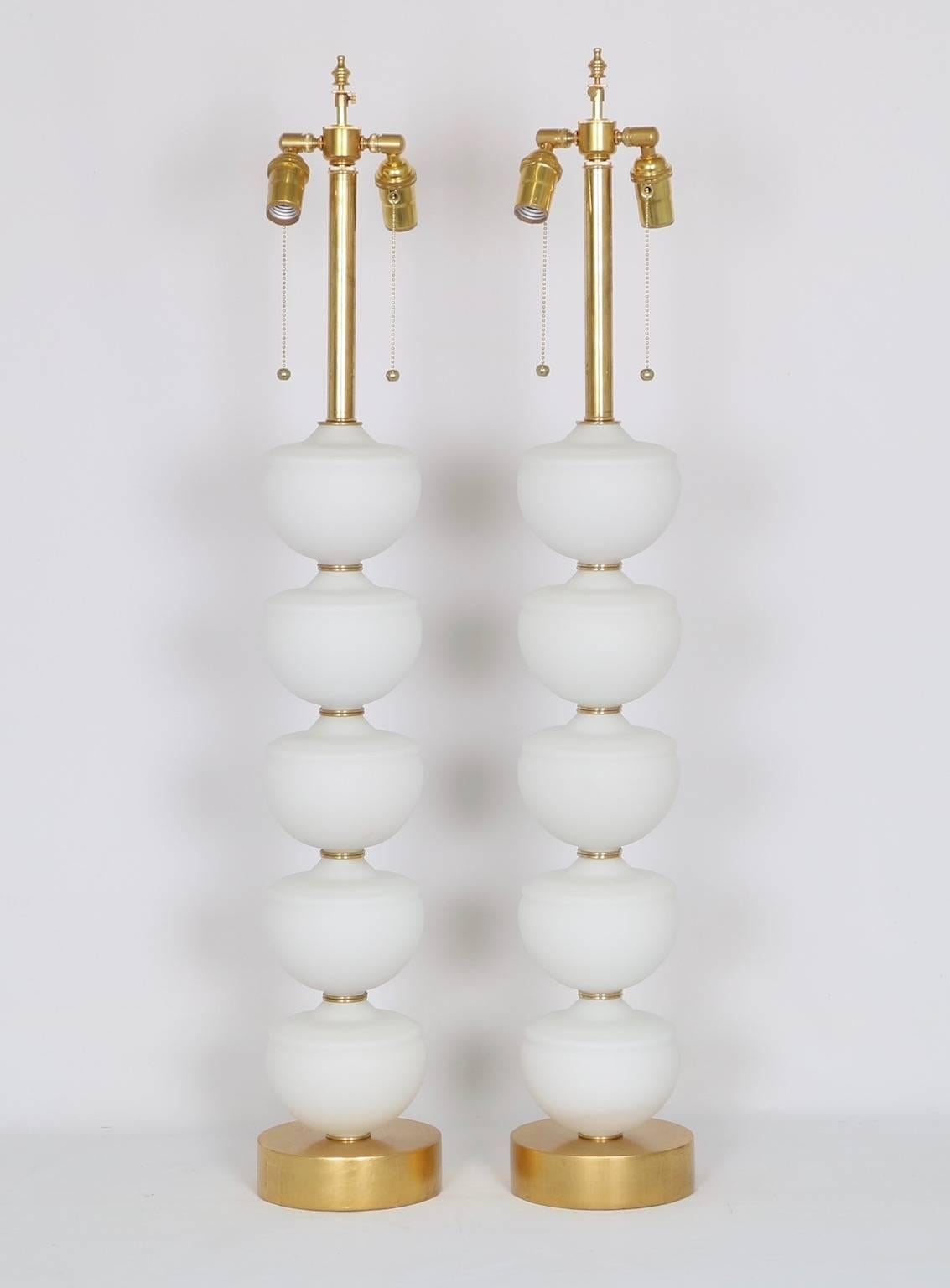 Pair of Hollywood Regency midcentury Murano glass lamps. Comprised of stacked frosted glass fonts mounted on a glitwood base. Fully restored with new wiring and hardware, including a double socket cluster. The noted height is to the finial. the