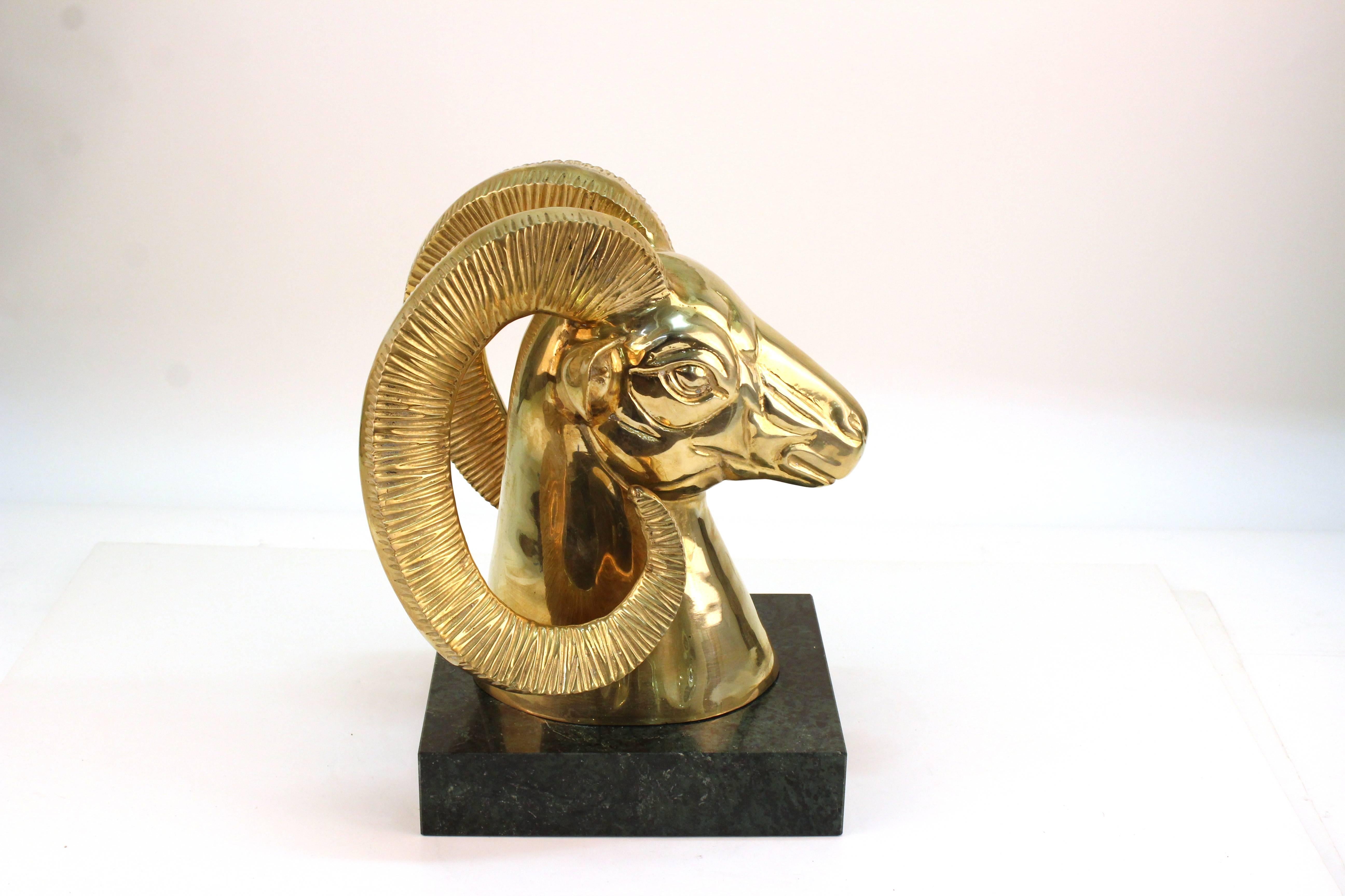 A brass sculpture of a ram's head. Crafted in polished brass on a black base. Minor wear to the brass finish and base consistent with use. In good condition.