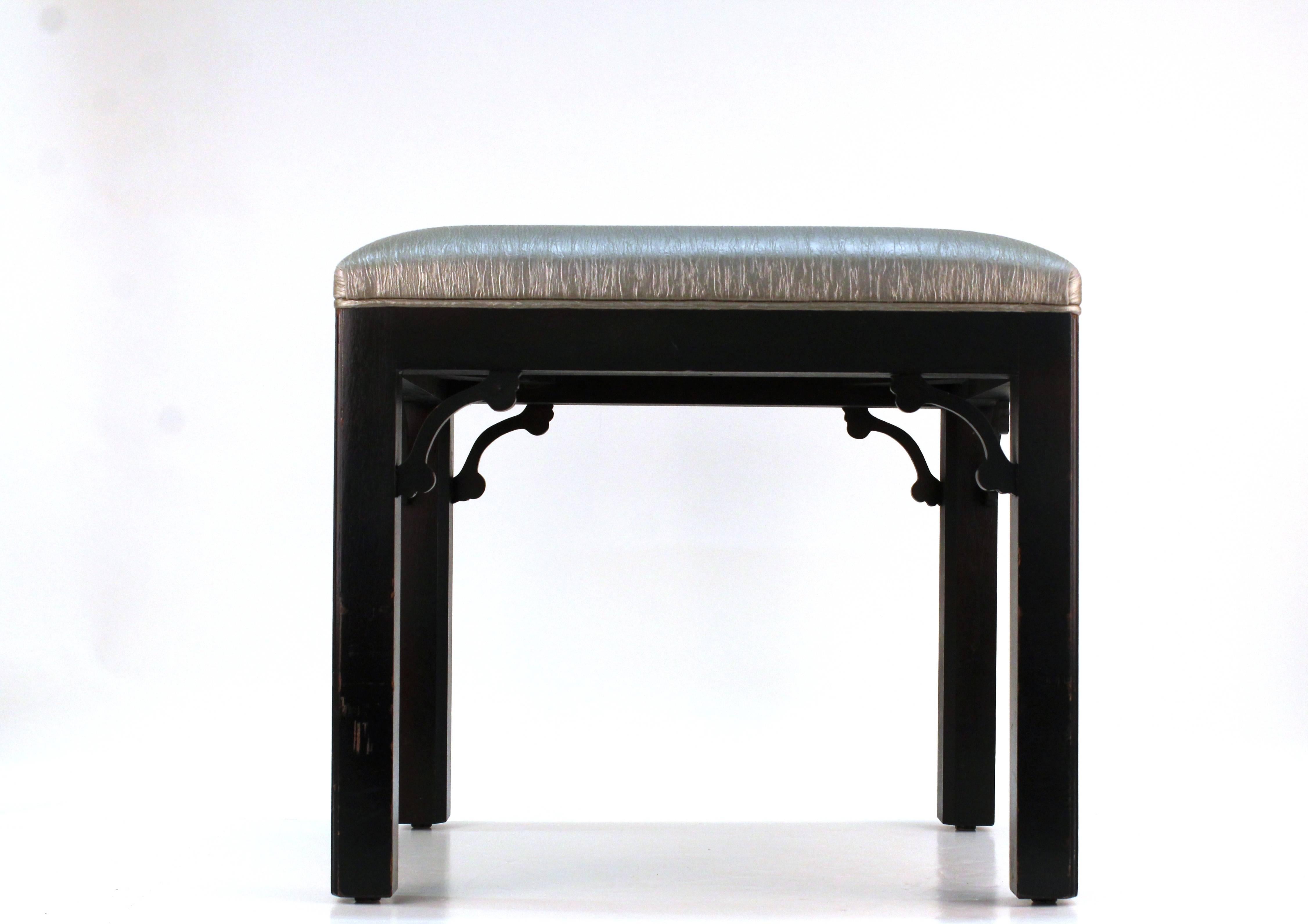 An four legged stool with Asian inspired motif. Produced in black painted wood and includes iridescent silver upholstery. Some wear appropriate to use but in good condition. 