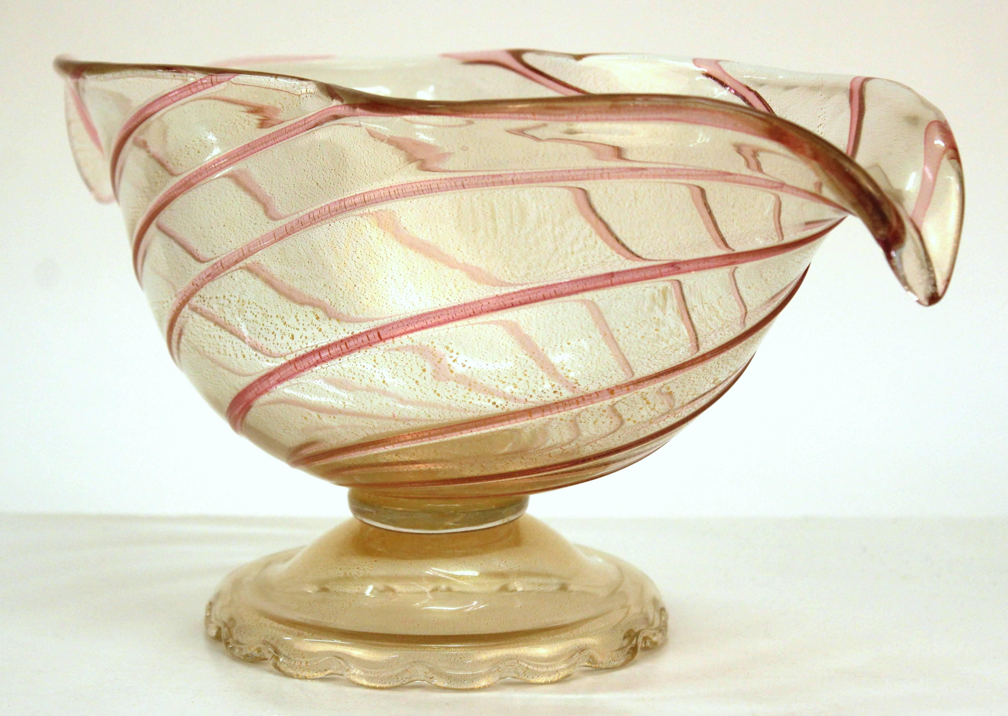 An elongated Murano glass vase or bowl with a pink swirl on a pedestal with footed base. The glass features gold inclusions. This vase is in good vintage condition and has wear consistent with age and use.