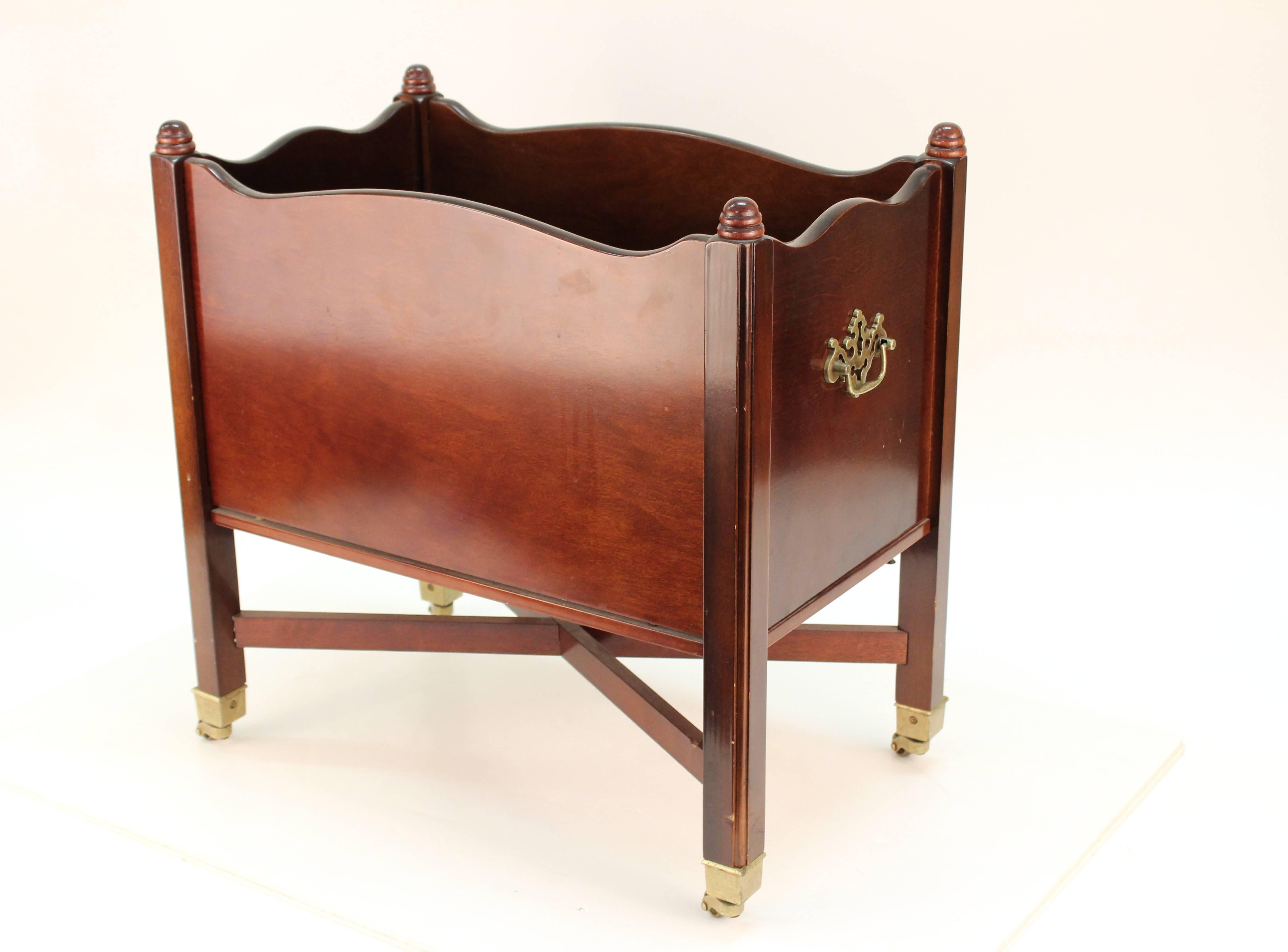 A 20th century Canterbury magazine stand. Features mahogany veneer and two slots. Includes cross base and small casters. Wear consistent with use. The piece is in good condition.