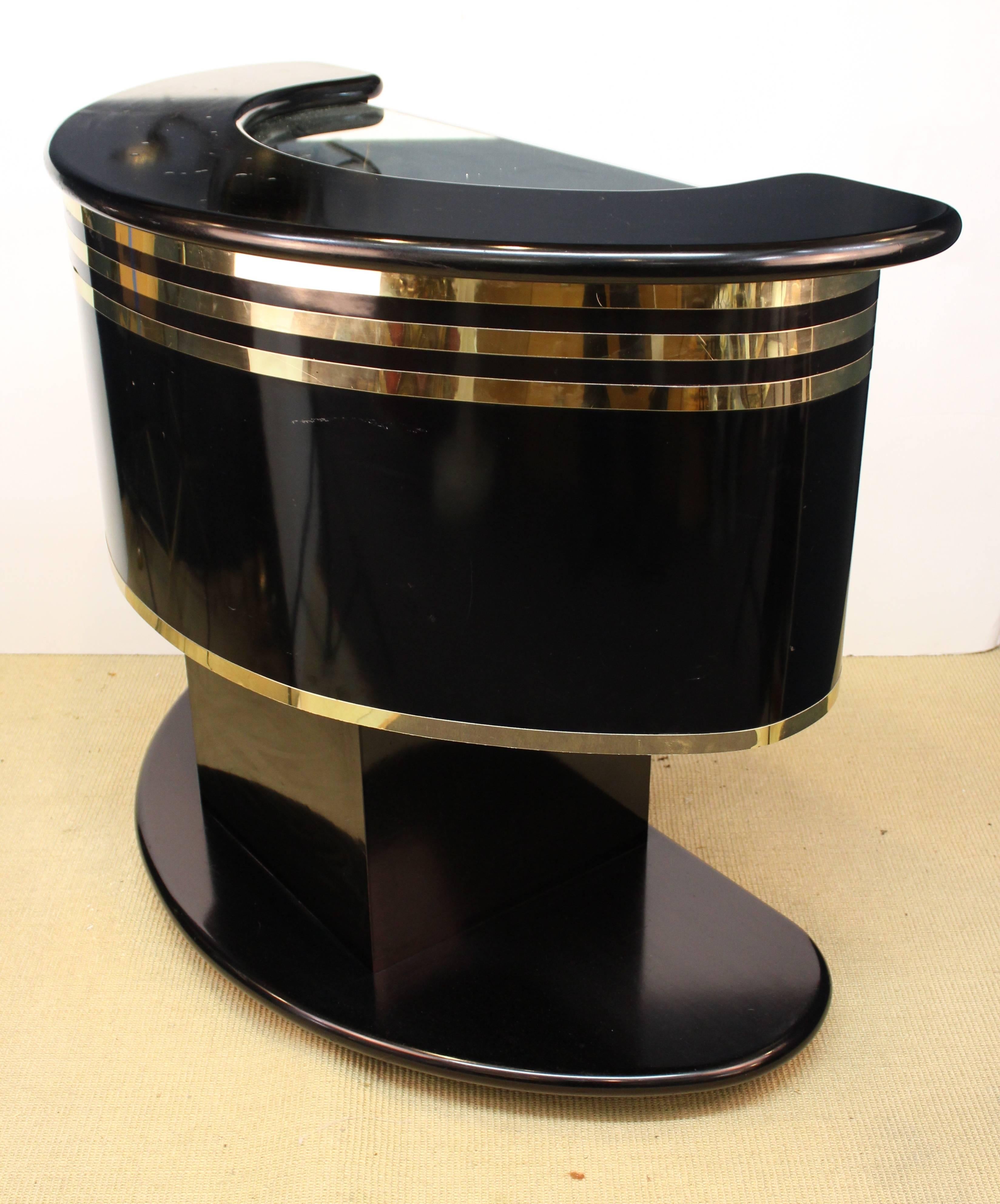 Hollywood Regency style half moon bar after Guzzini. Crafted in black laminate with mirrored glass accents and wood. Some bubbling of the laminate on the bar top and a small nick to the finish on the back. The bar remains in good vintage condition.