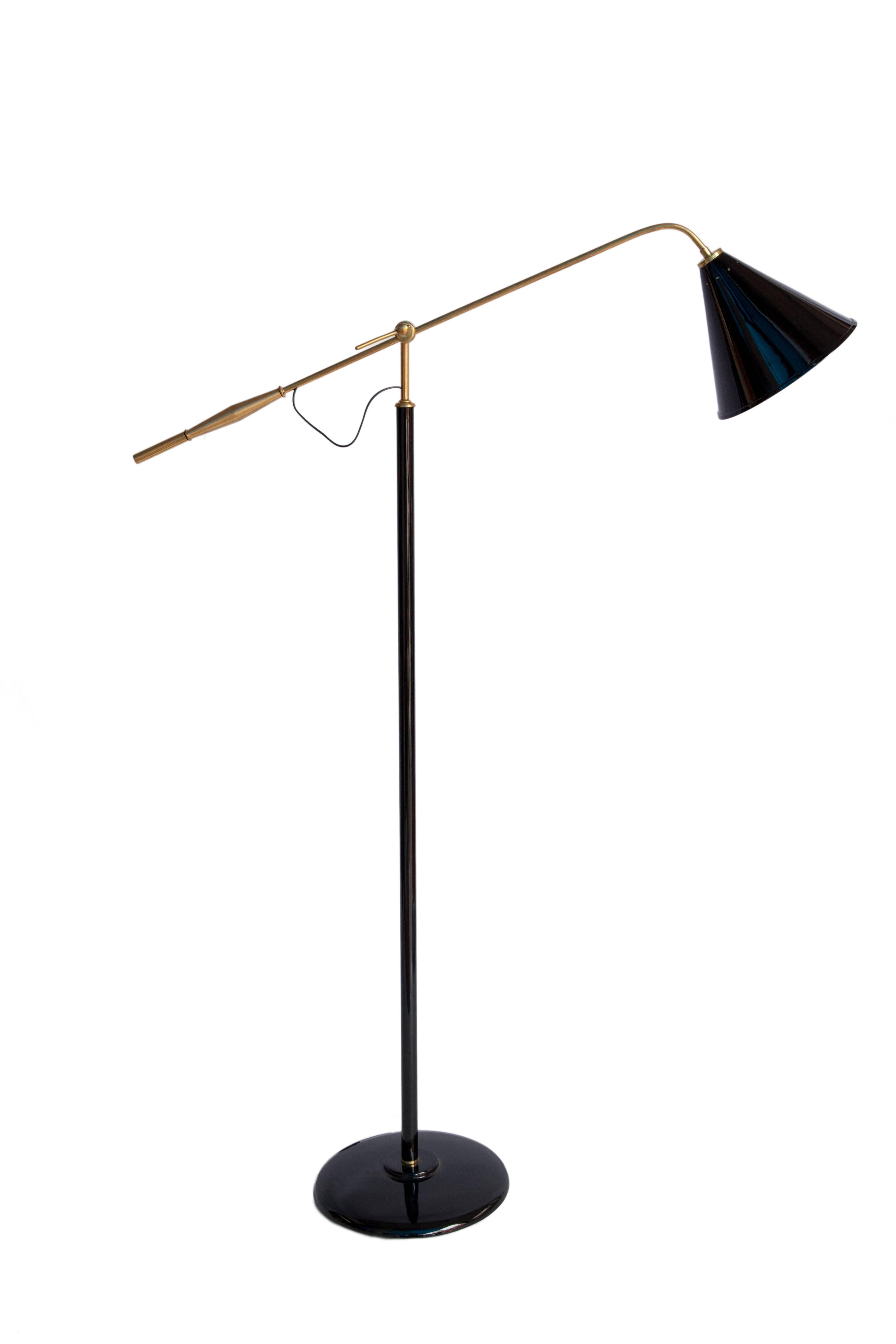 A midcentury floor lamp in brass and black painted iron from Brazil, circa 1950s. This floor lamp has a modernistic conical shade and articulating arm. It is in good vintage condition and has wear consistent with age and use. 111459.