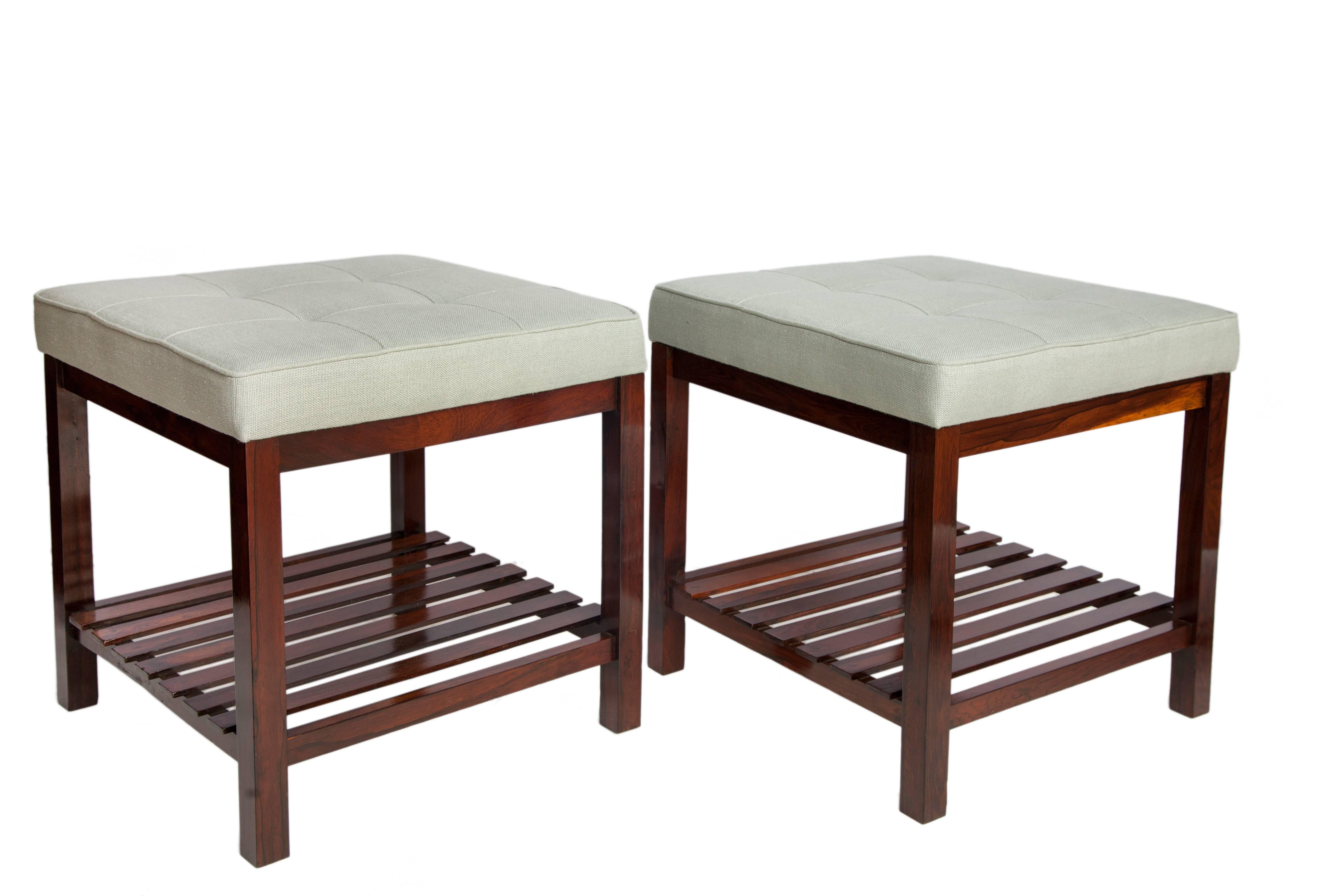 Mid-Century Modern stools in Brazilian jacaranda with slatted lower shelf. Each is recently reupholstered in light green tufted linen. The stools remain in good vintage condition and have wear consistent with age and use. Listed dimensions are per
