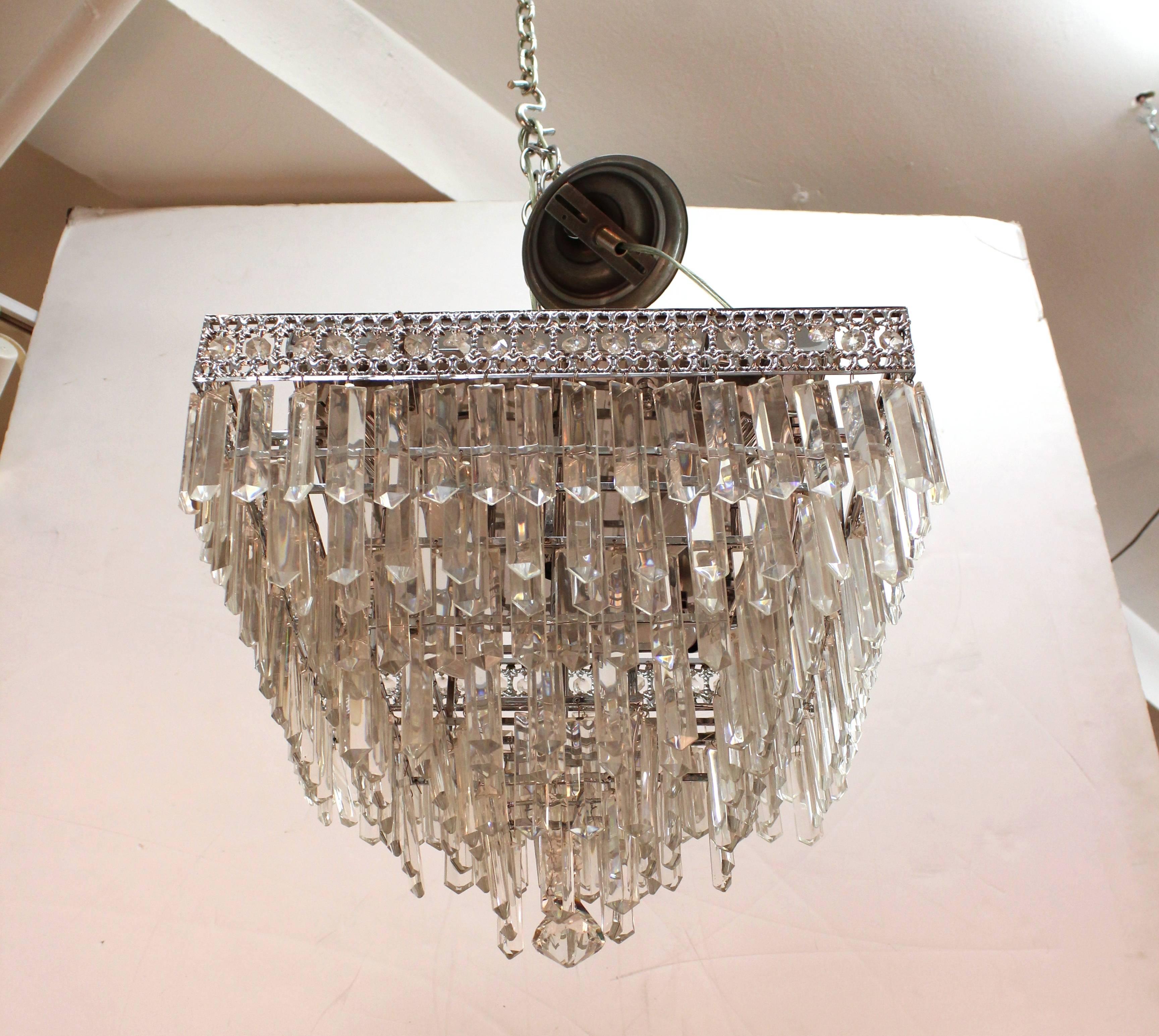 A Mid-Century Modern Italian rectangular chrome tiered chandelier with Murano cut crystal prisms. The chandelier was made in the 1950s and has recently been rewired to US standards. The piece takes five candelabra base bulbs. In excellent vintage