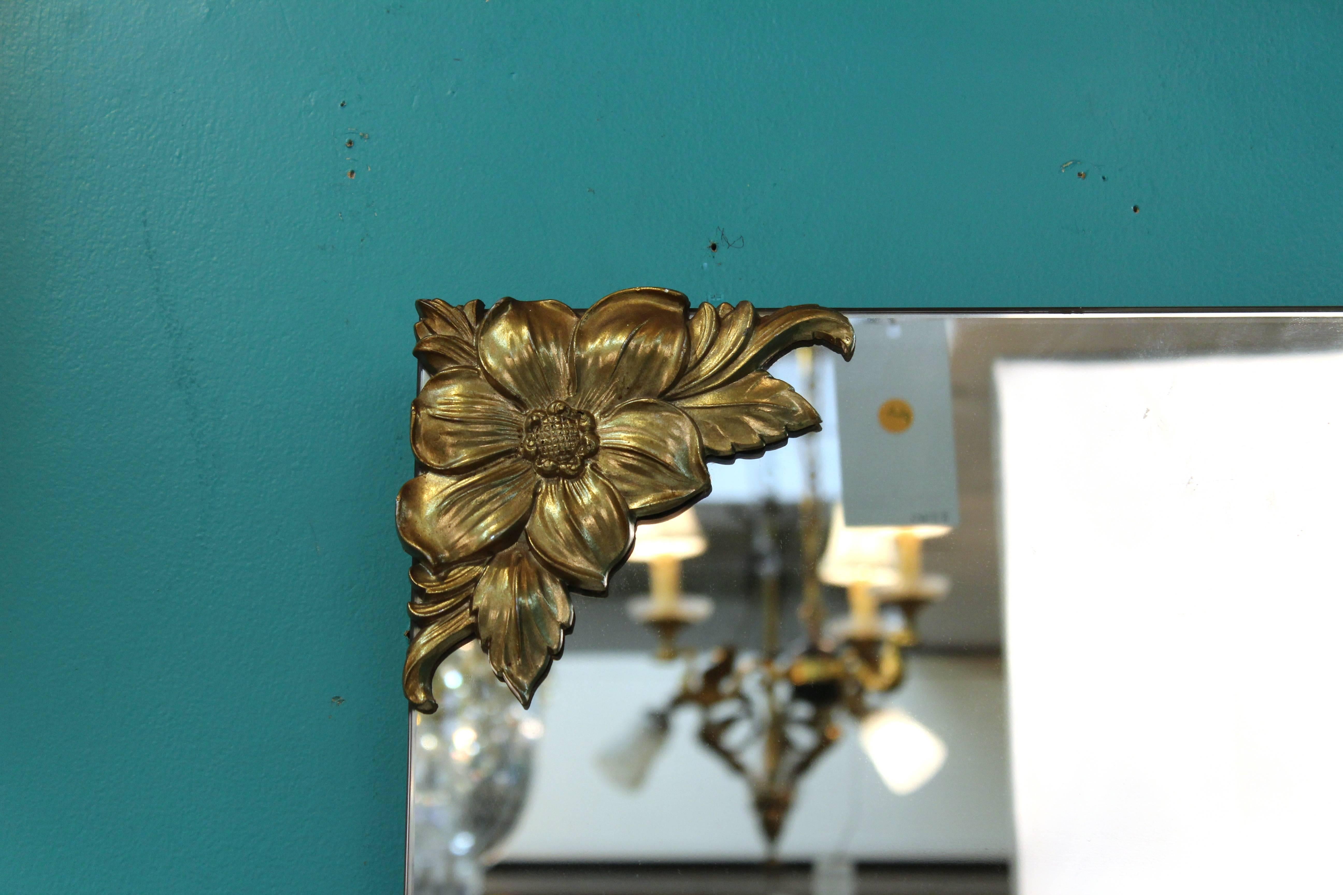 Large American Hollywood Regency mirror with brass floral decor on each one of its corners. Due to its design, this mirror can be hung either horizontally or vertically. In very good vintage condition.