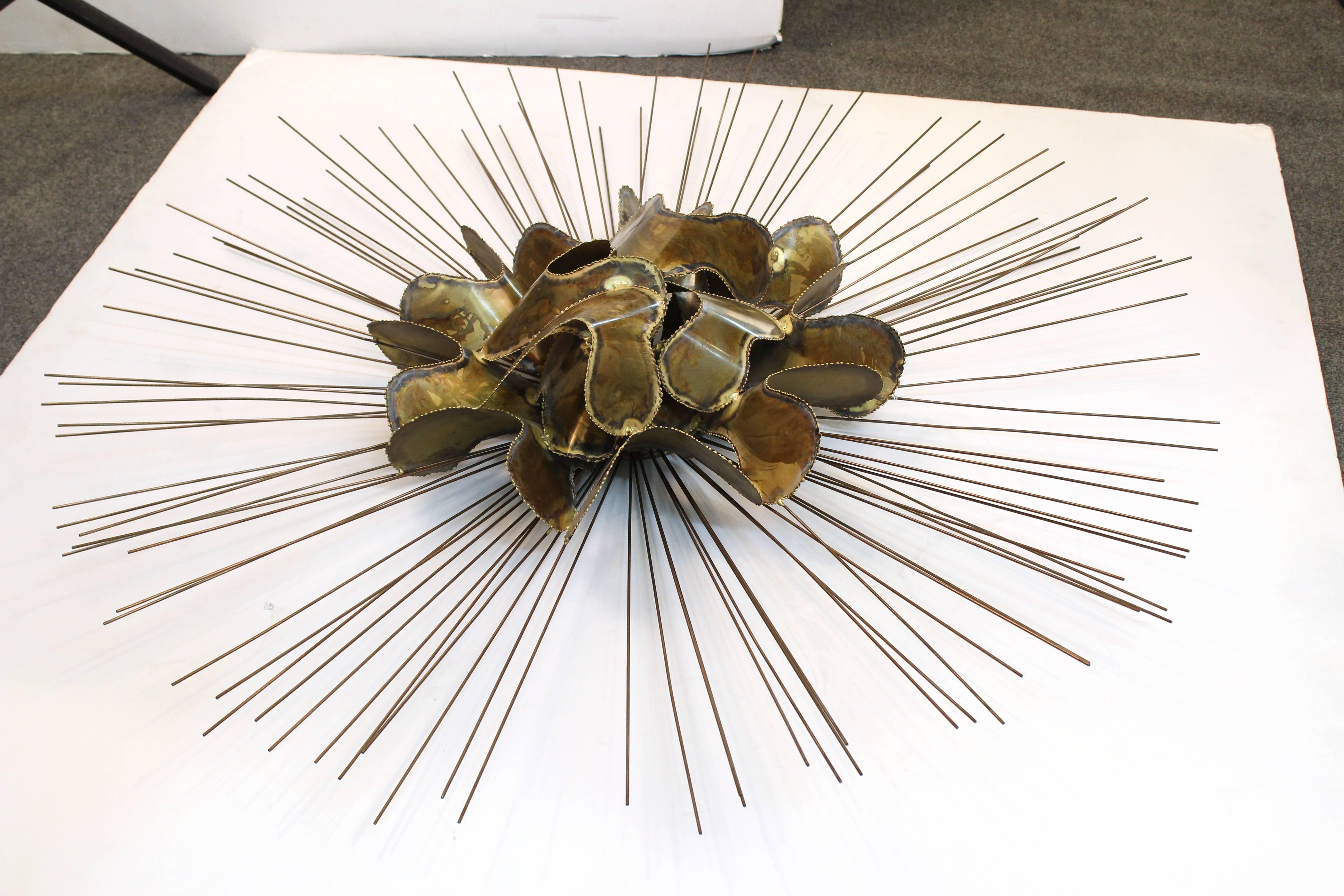 A Mid-Century Modern brass wall sculpture in the style of Silas Seandel, in the shape of a large sunburst. The piece was made in the United States in the 1970s. In great vintage condition with wear appropriate to age and use.
