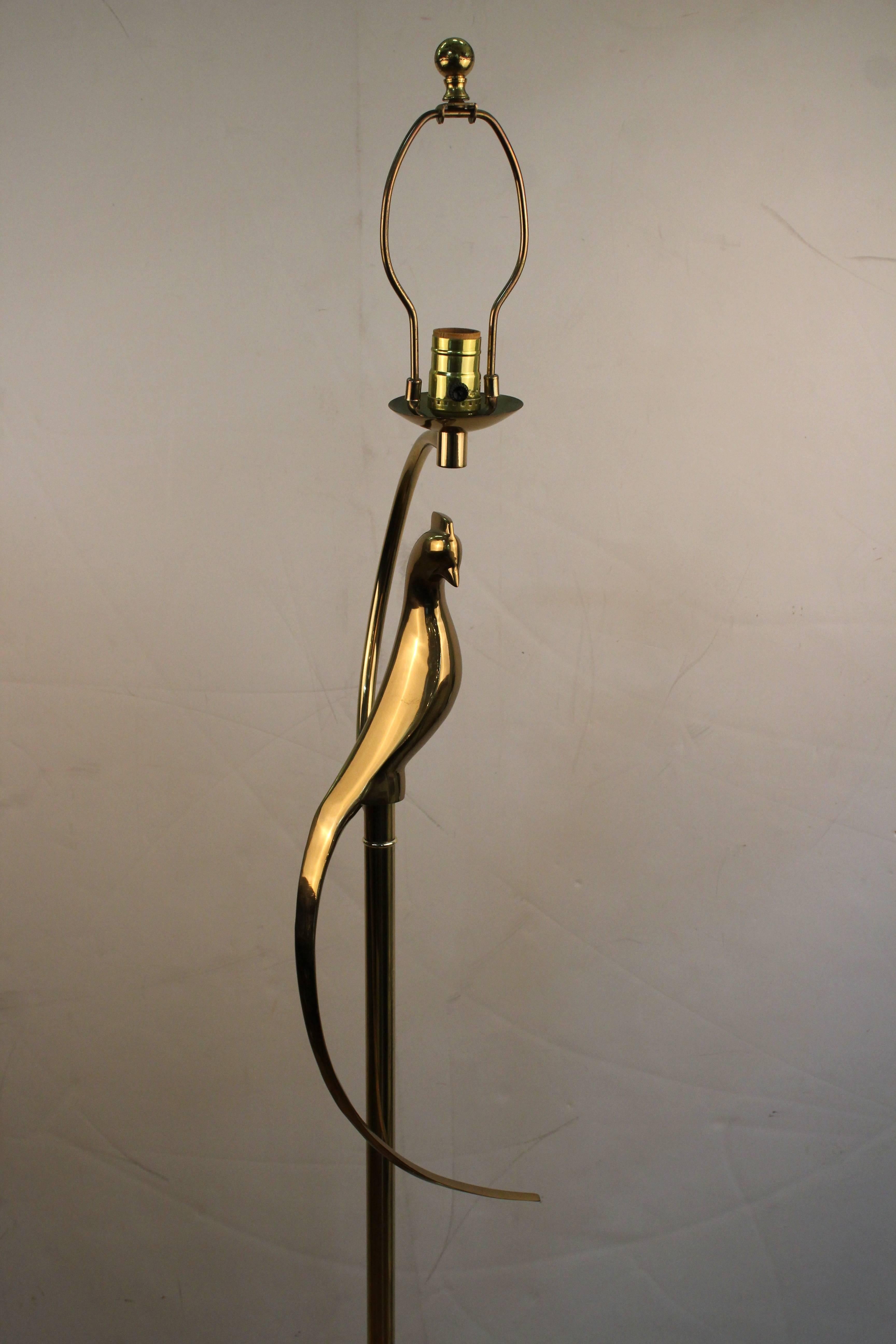 A Mid-Century Modern floor lamp made of brass. The lamp has an exotic bird sitting on a perch atop of it. The lamp is in overall great vintage condition with wear consistent with age and use.