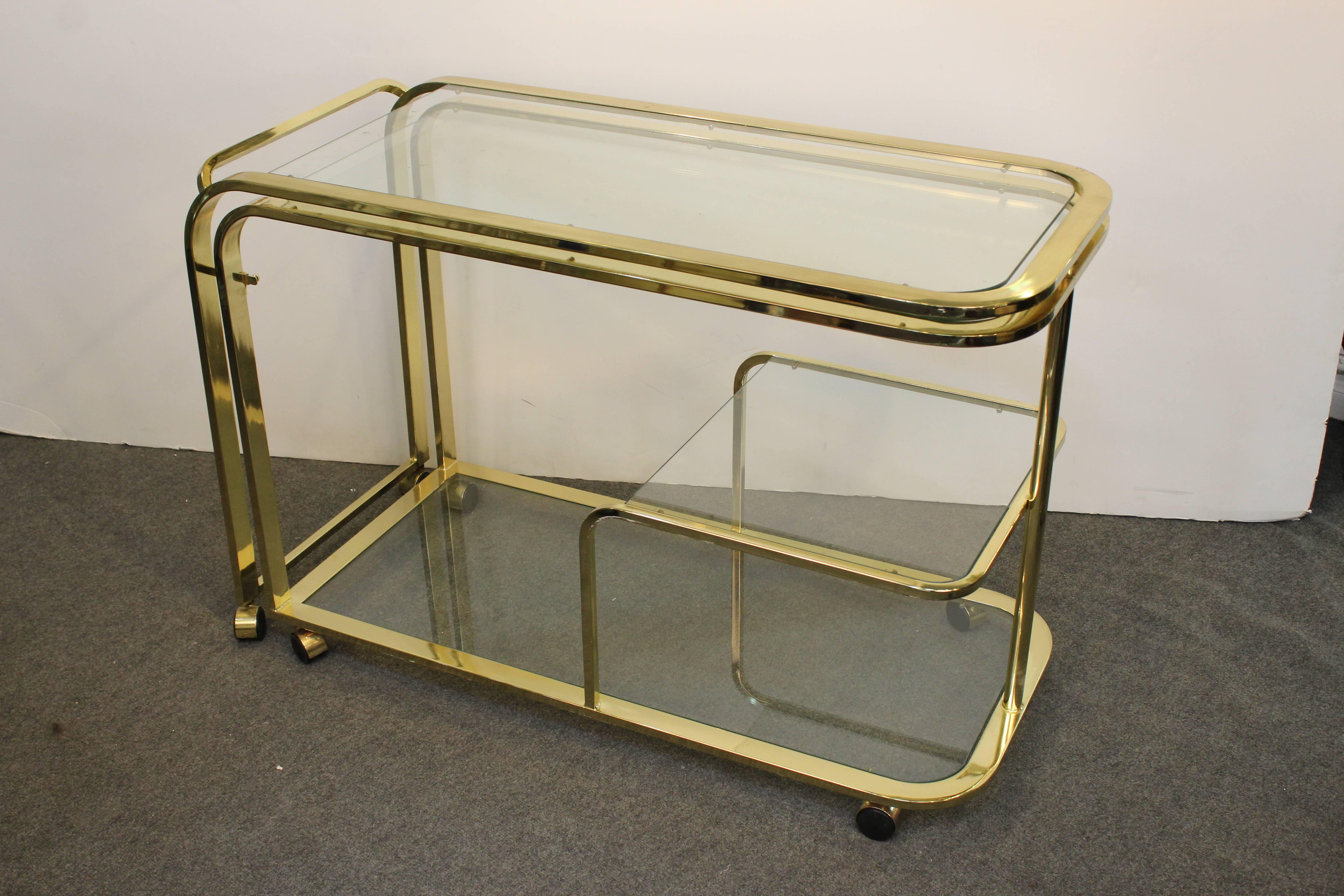 A Hollywood Regency monumental expandable bar cart made by Design Institute of America. The cart is made of brass and can unfold into a bar twice its original size. Made in the 1970s in the United States. In great vintage condition.
