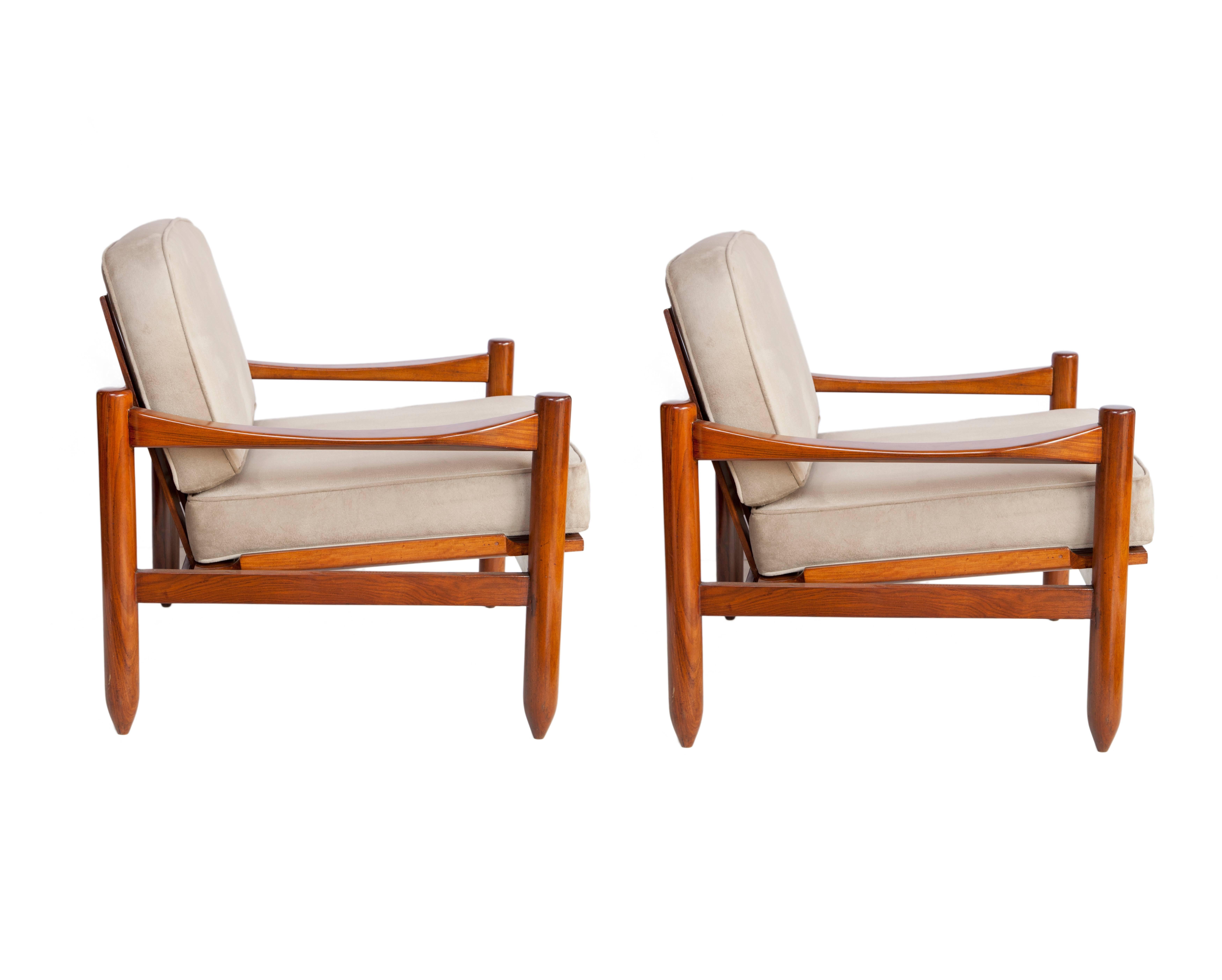 Michel Arnoult armchairs produced in Brazil, circa 1960. The frames are crafted in Jacaranda and stand on four pillar legs with pointed feet. The arms feature a curved indent for style and comfort with a planked backrest. Cushions recently
