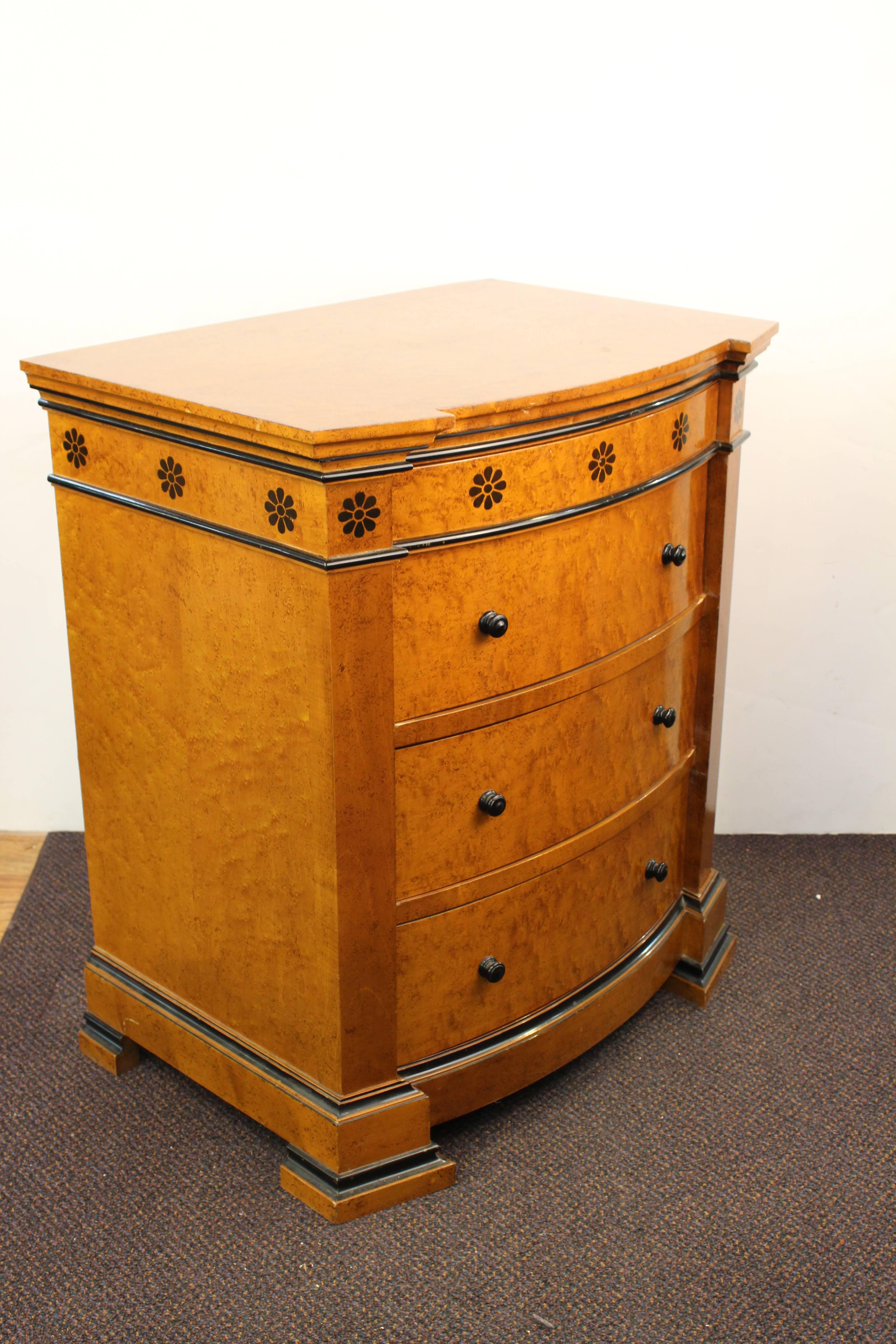 A pair of wooden nightstands in the Art Deco style, featuring three large sized drawers and a shallower drawer on top. A decorative border of inlaid rosettes runs around the upper part. The pair is in good vintage condition with age appropriate wear