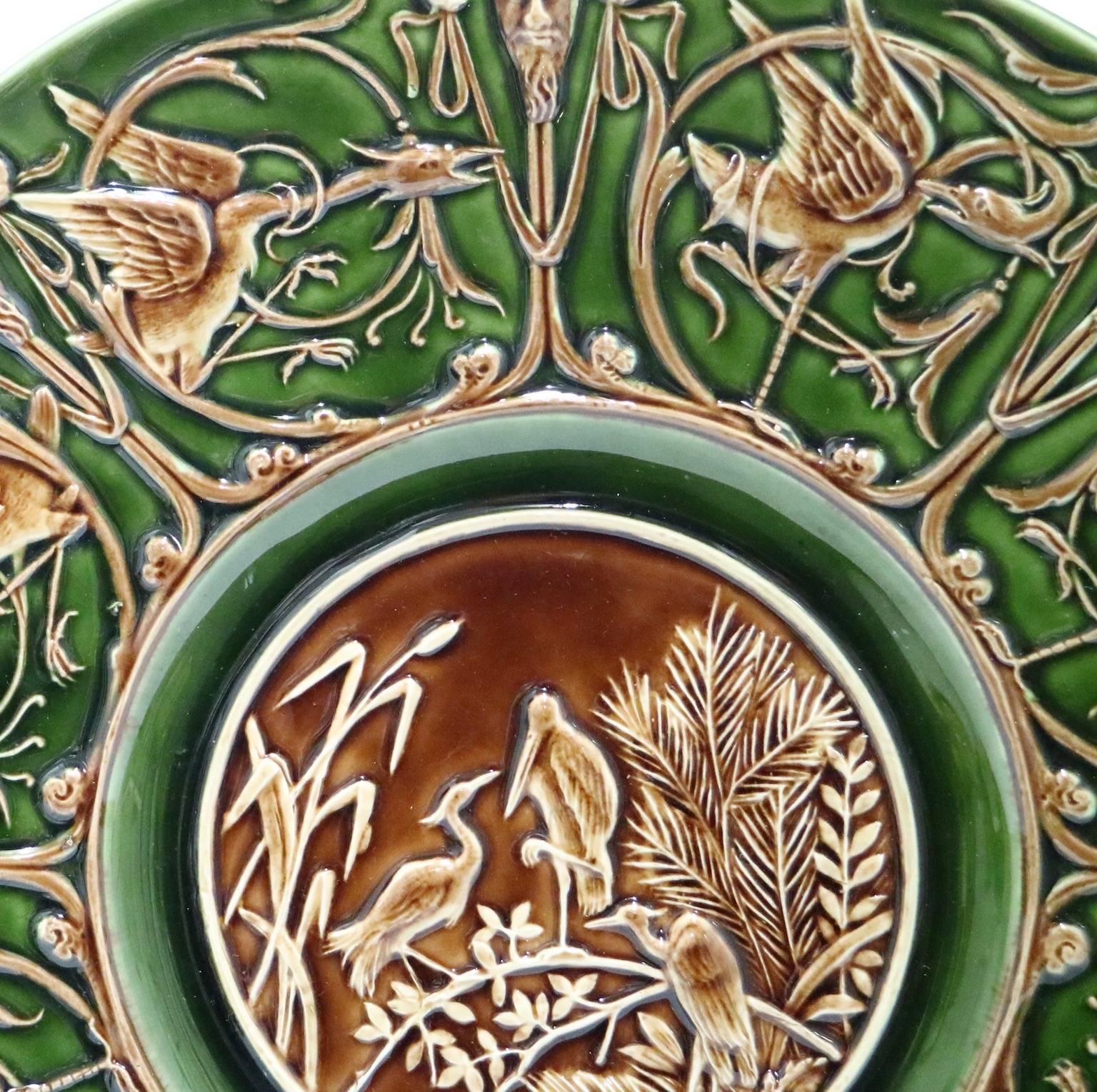 An antique Austrian majolica plate by Schutz Blansko dating from the late 19th century. The plate, glazed in green and brown hues, depicts raised herons, satyrs, foliage and scroll-work throughout. This plate is in excellent vintage condition and