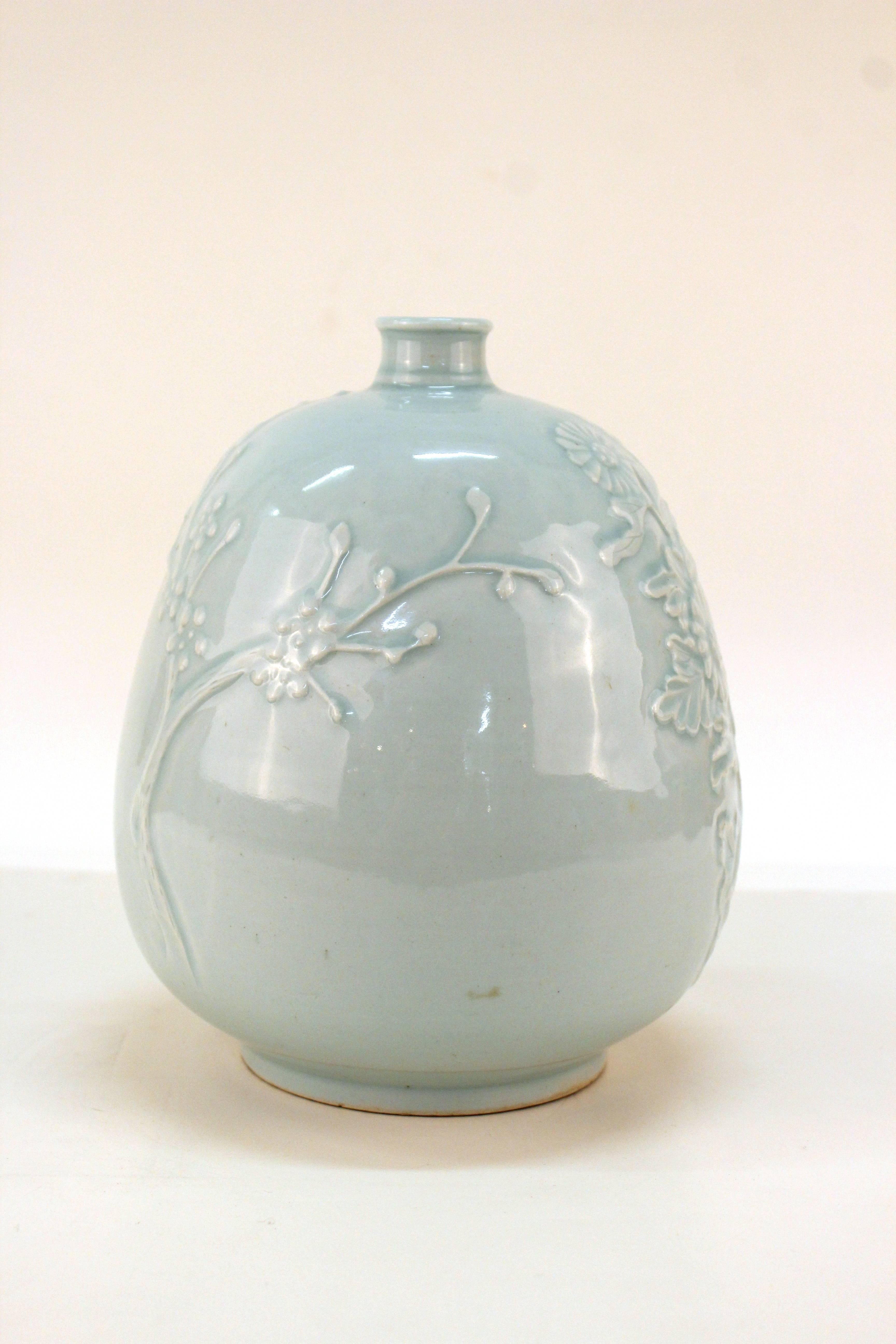 Pottery vase with celadon glaze from Korea. Decorated with had-applied raised cherry blossom branches and sprays of daisys. Has unknown makers mark. Wear consistent with age and use. The vase is in good condition.