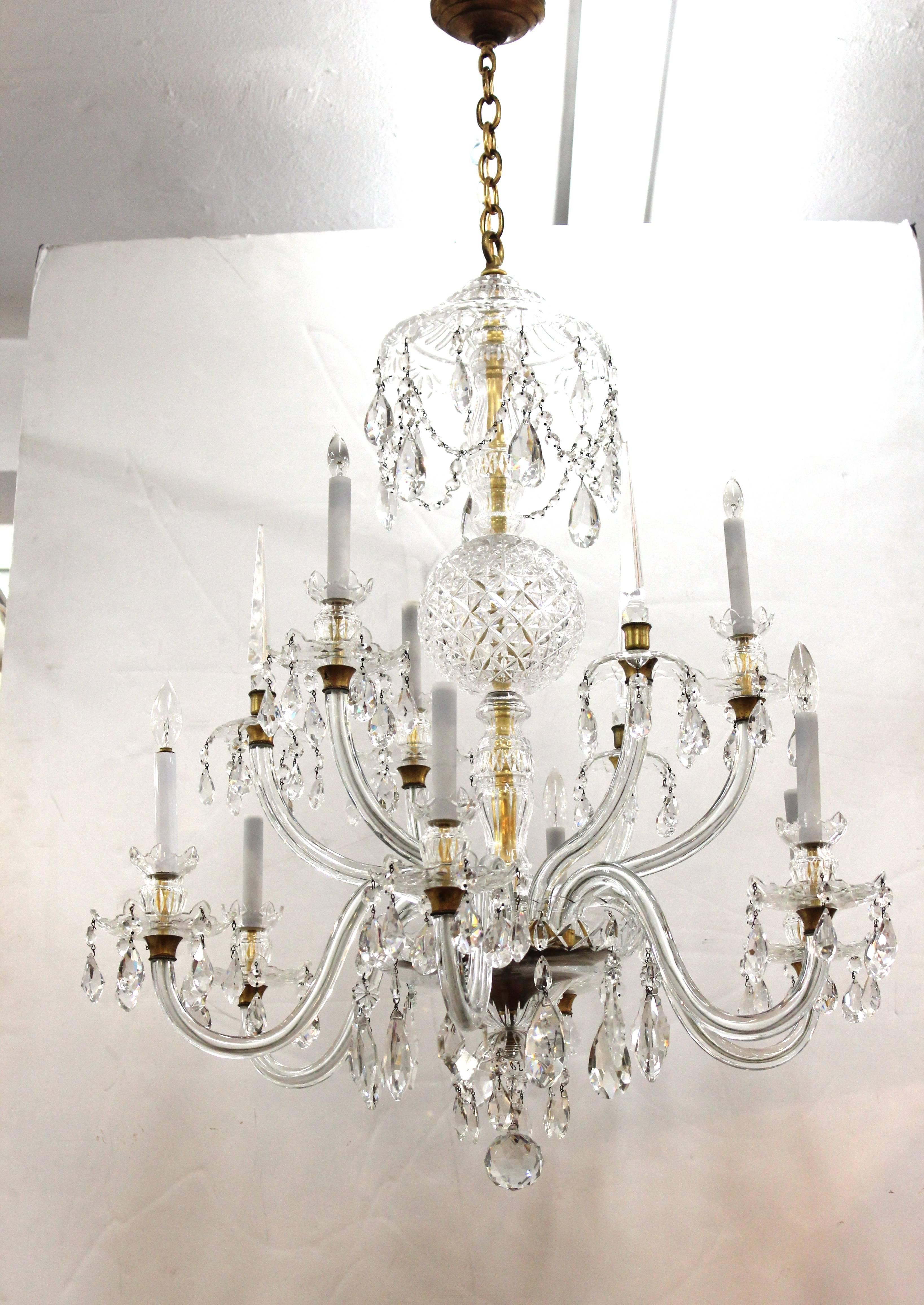 Crystal chandelier by Waterford. Features cut crystal sphere and multiple scrolled crystal arms with faux candle sockets. Cascading crystal drops and beads dangle from each part of the chandelier. Wear consistent with age and use. The piece is in