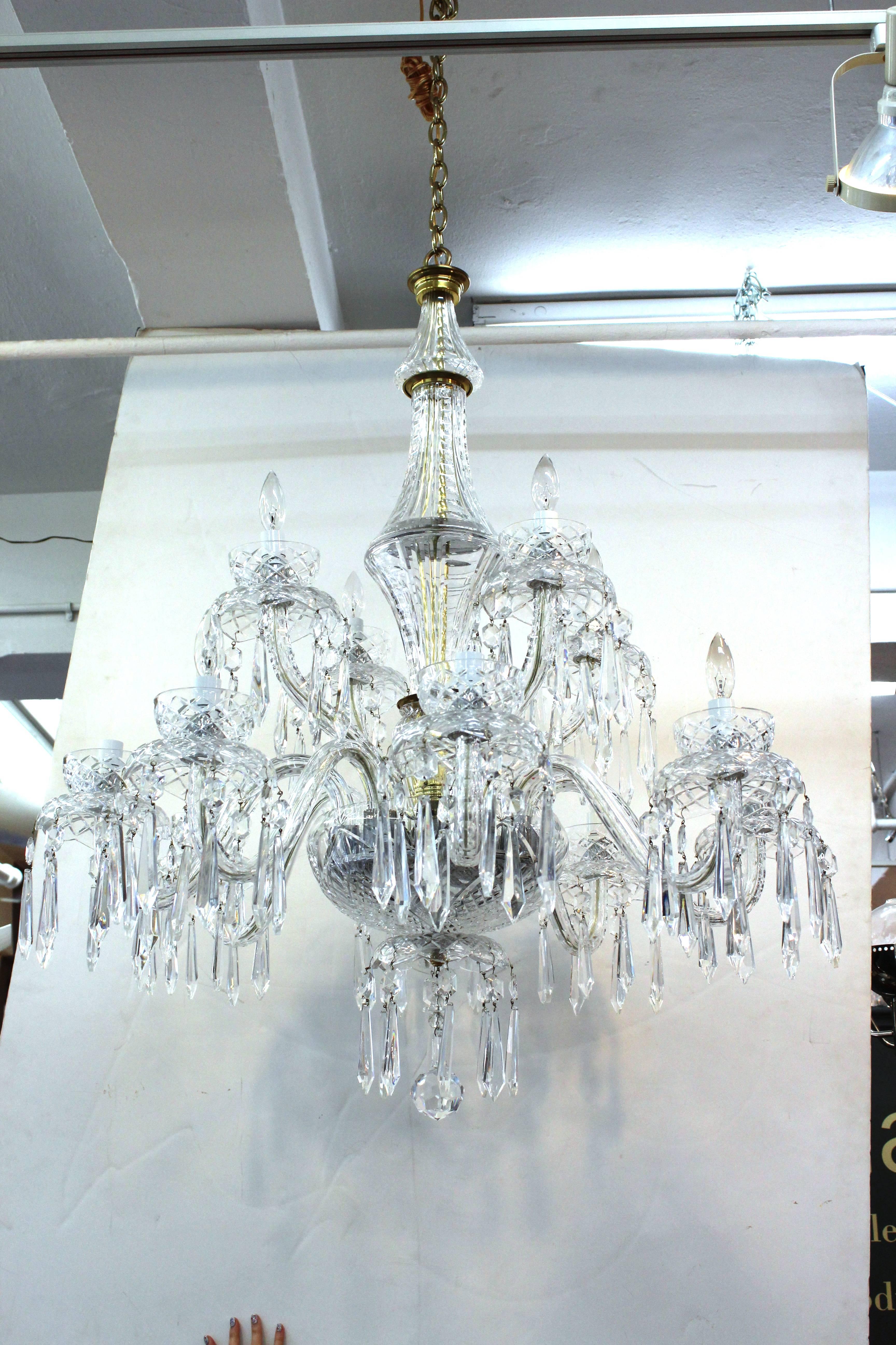 Crystal chandelier by Waterford. Features an intricately cut crystal body and scrolled arms. Includes levels of long cascading cute crystal droplets. Wear appropriate to age and use. The chandelier is in good condition.