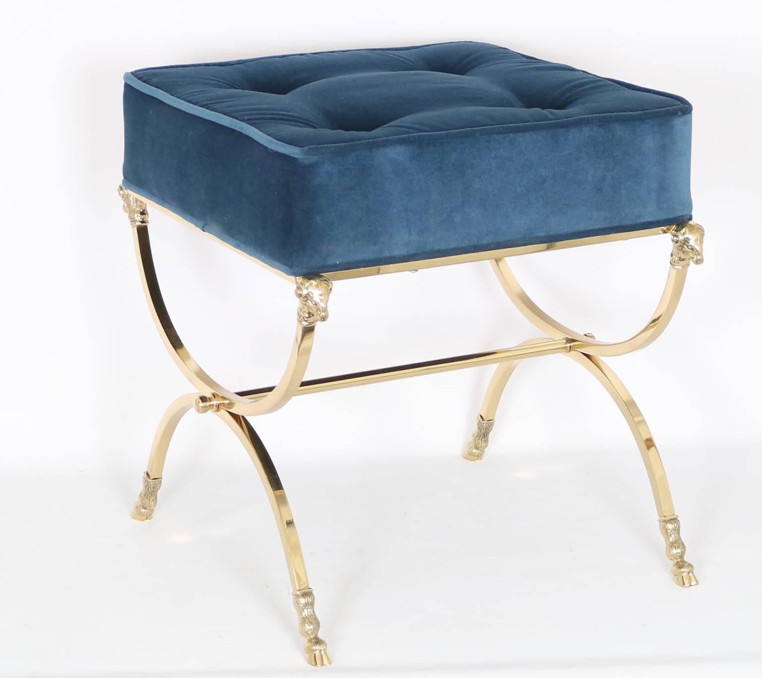 Italian brass campaign stool in the Hollywood Regency style with blue velvet upholstery and ram's head and hoof motifs from, circa 1950. This stool has been fully restored and newly upholstered. The piece is in excellent vintage condition and has