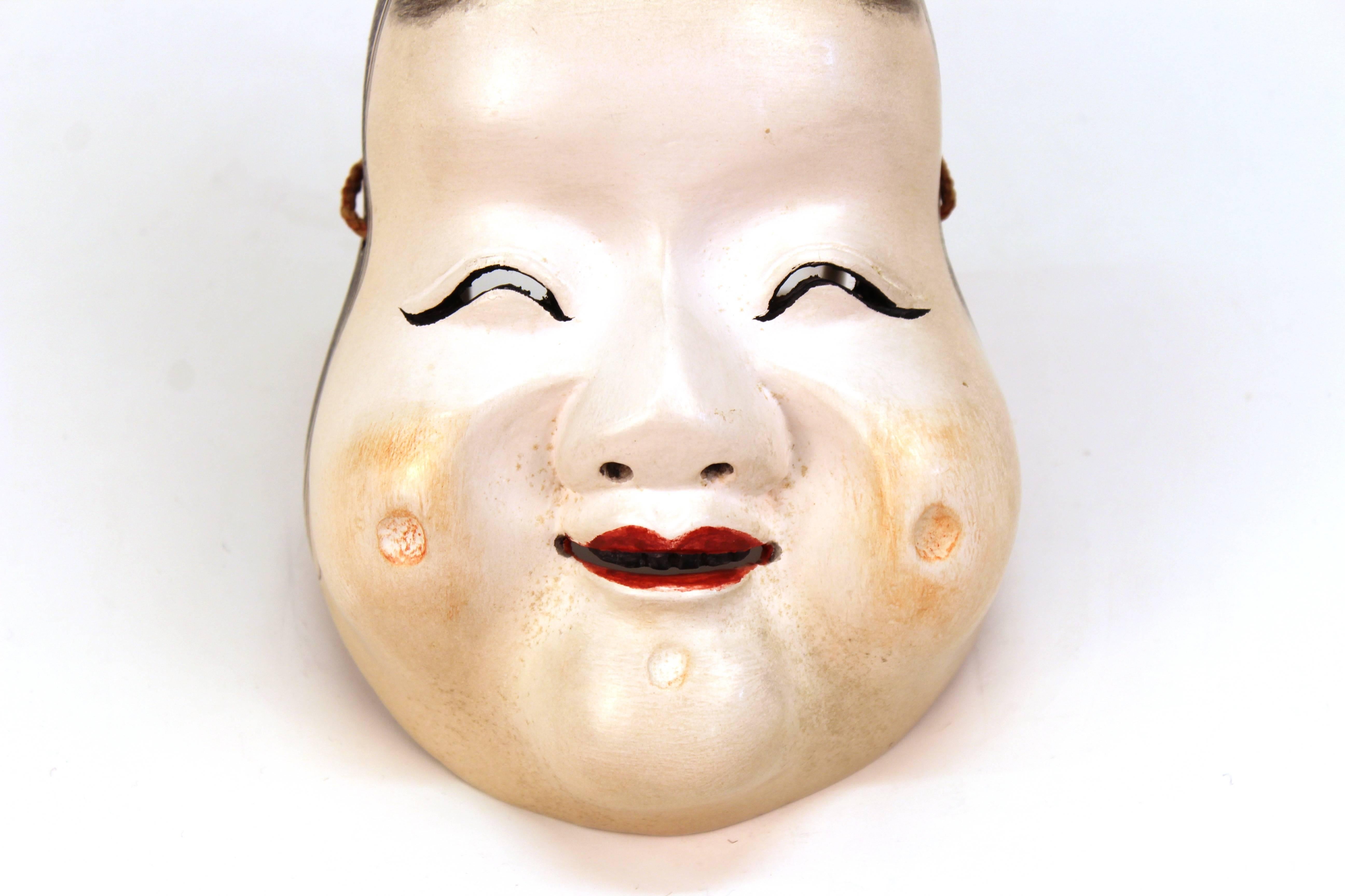 A Japanese sculpted wood theater mask depicting Okamo, the goddess of happiness. The piece was made during the Meiji Period (1868-1912) around 1890-1910. In very fine vintage condition.