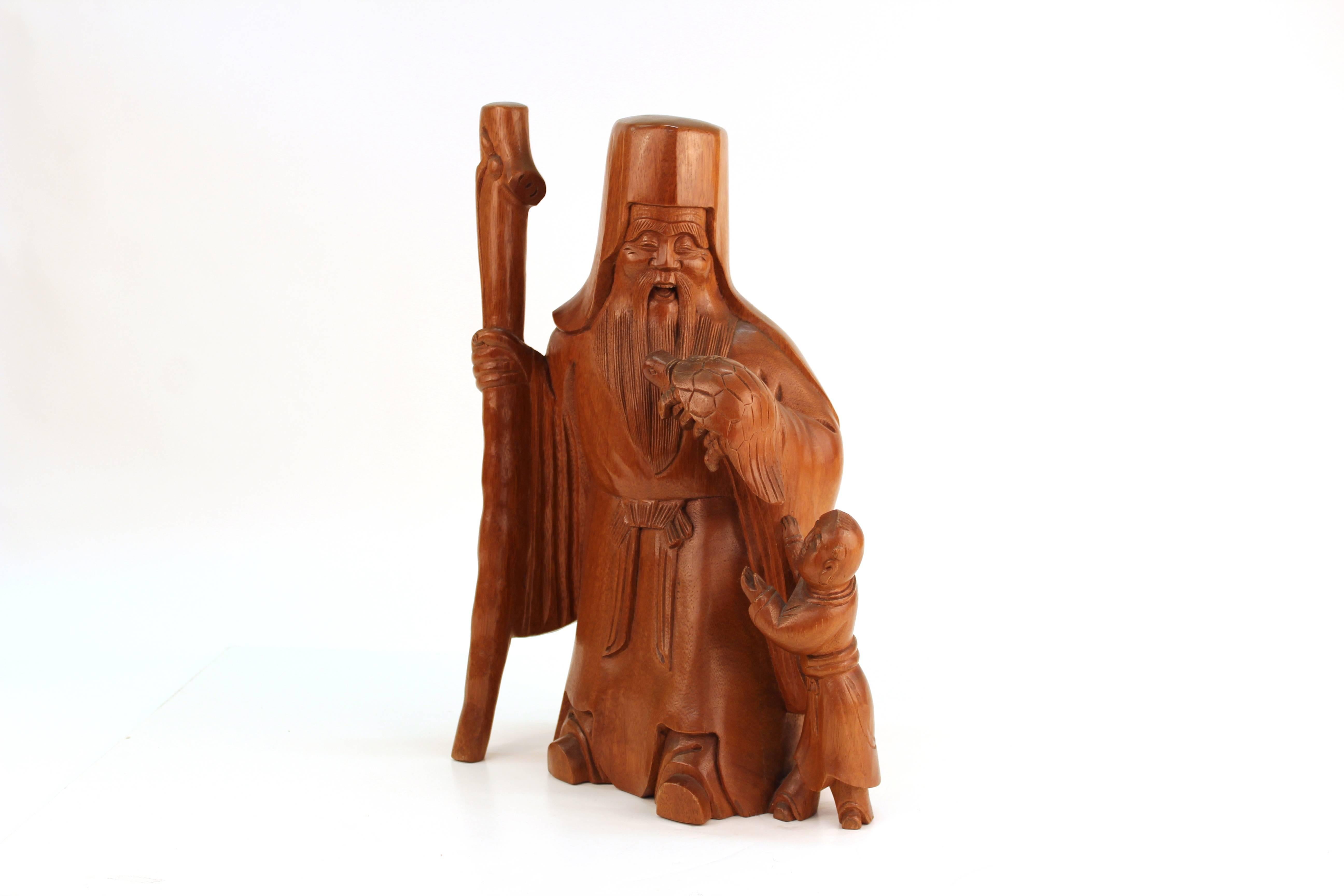 Okimono japonais en bois de palme sculpté de Jurojin (dieu de la longévité avec une tortue). Symbole de longue vie, la sculpture représente également un jeune garçon qui incarne le début de la vie. Sculpté d'une seule pièce de buis avec une belle