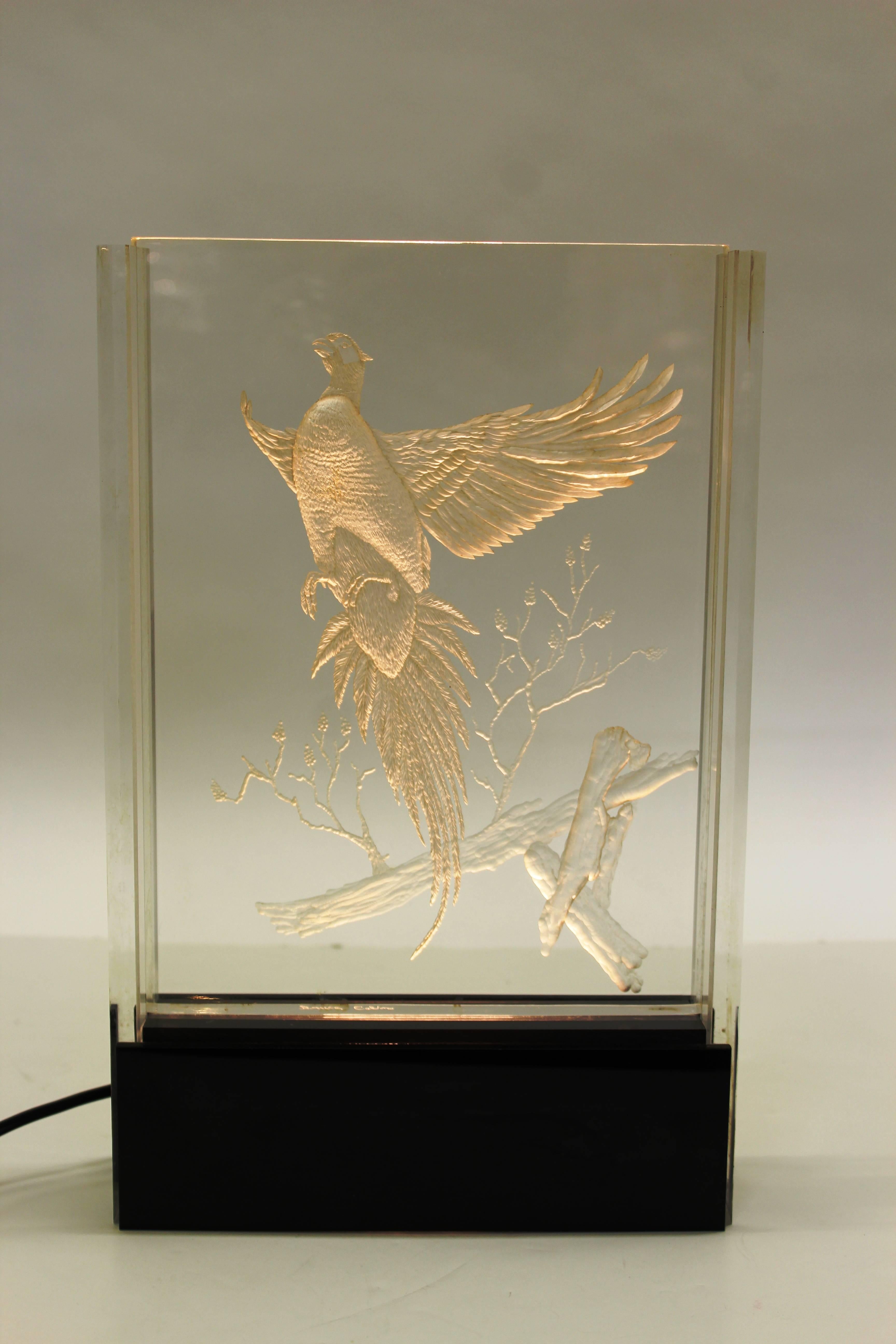 A Hollywood Regency table light made with an etched/engraved lucite panel depicting a pheasant in flight. The scene lights up when the light in the base is turned on. In great vintage condition.